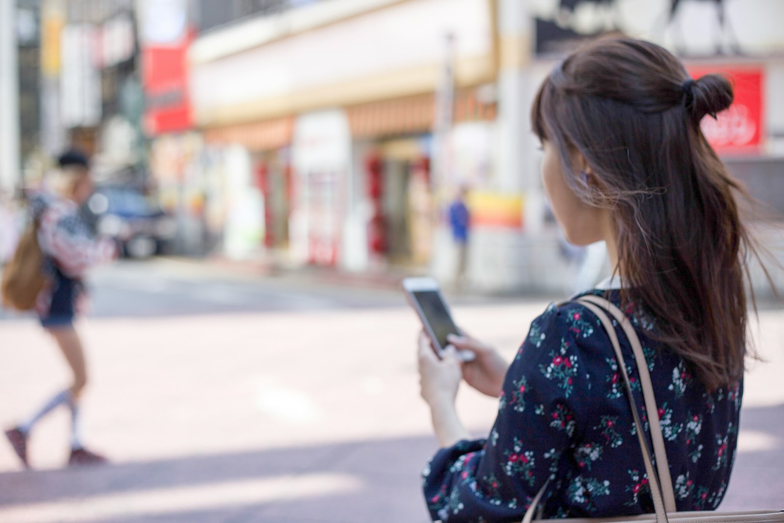 Femme jeune utilisant un smartphone à un coin de rue