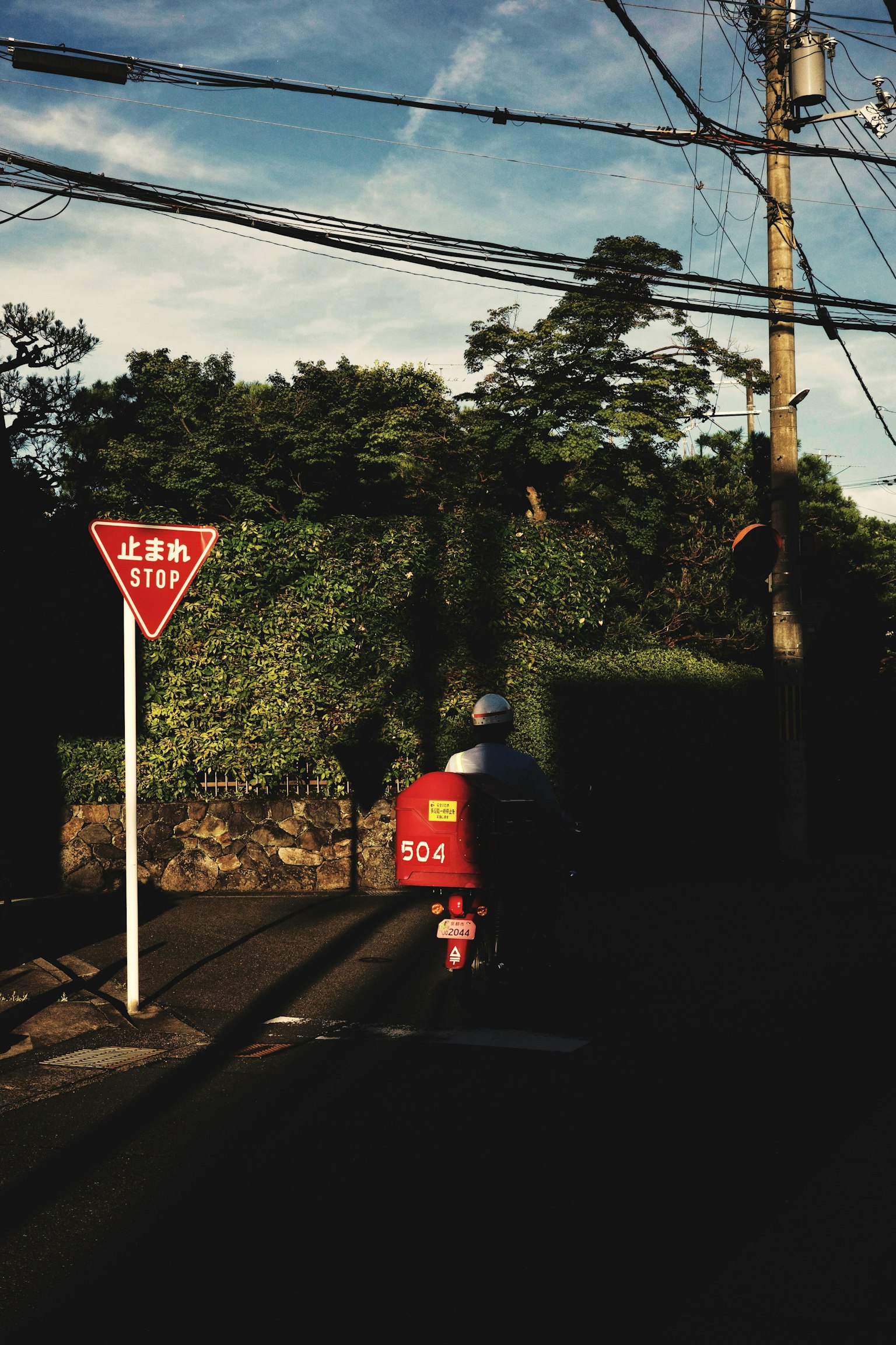 Một chiếc xe máy màu đỏ đi qua ngã tư có biển báo nhường đường