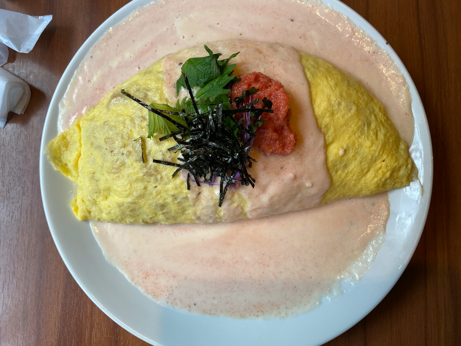 Omelette rice topped with seaweed and tomato in creamy sauce