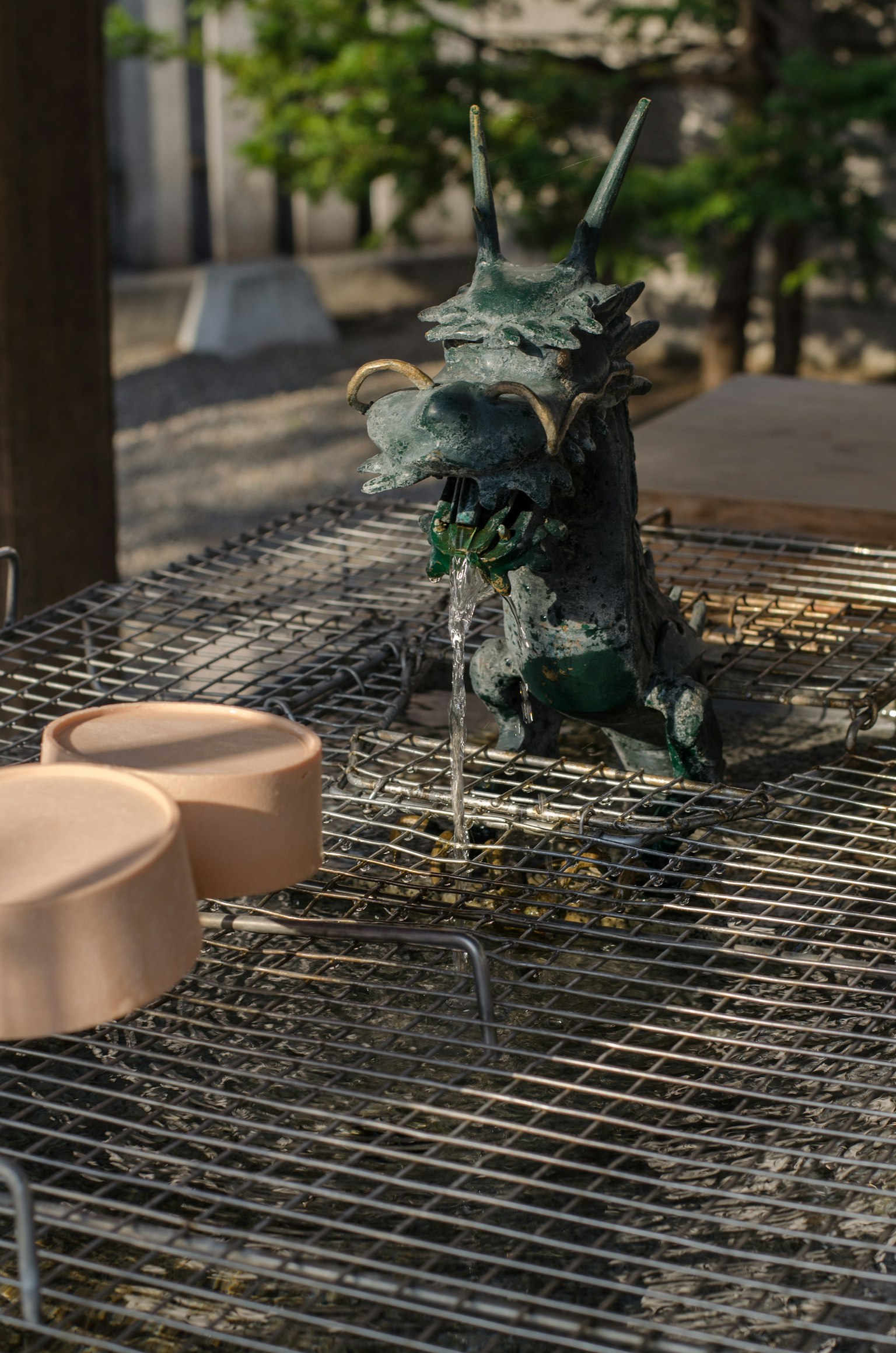 A dragon sculpture pouring water with two ceramic containers nearby