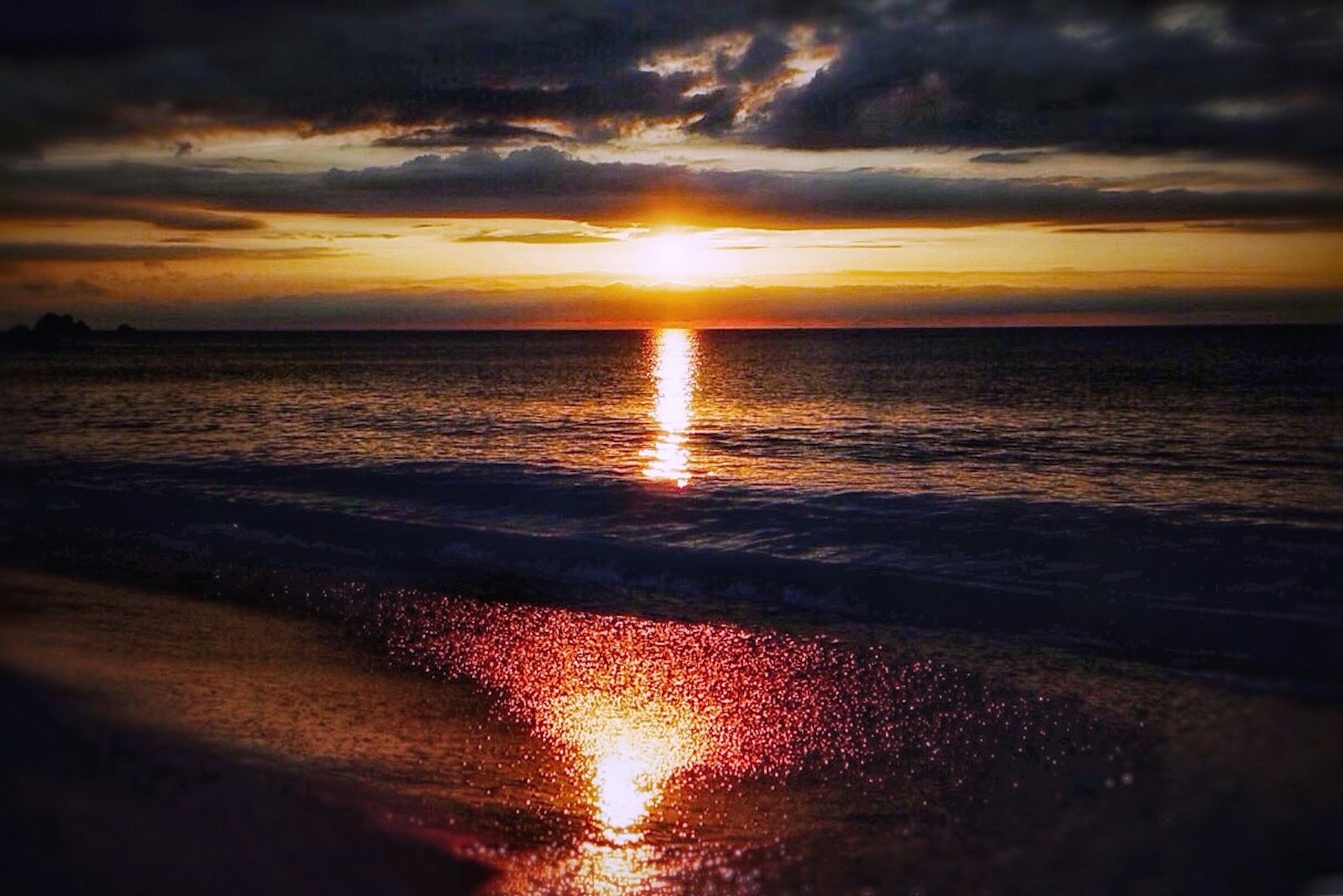 Belle scène de plage avec le coucher de soleil se reflétant sur l'eau