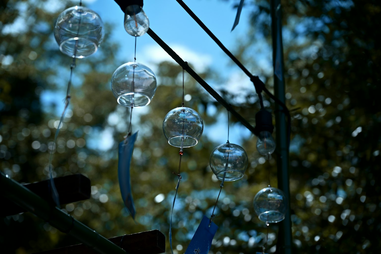 Windspiele aus klarem Glas und blauen Bändern schwingen unter einem blauen Himmel