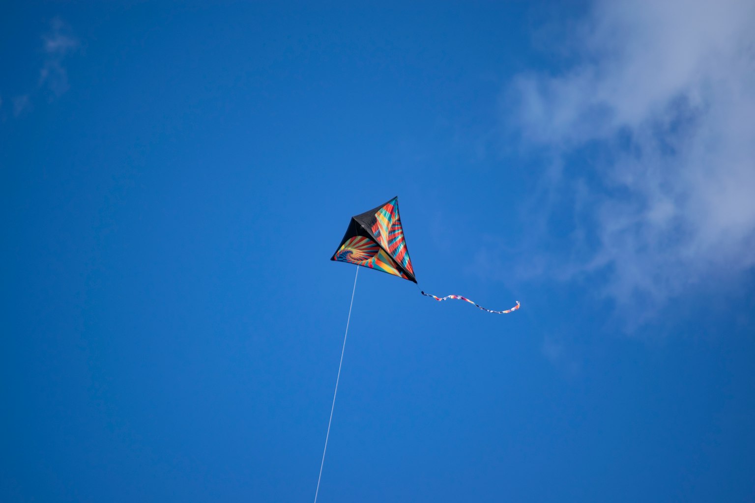 Un aquilone che vola in un cielo blu con il suo filo