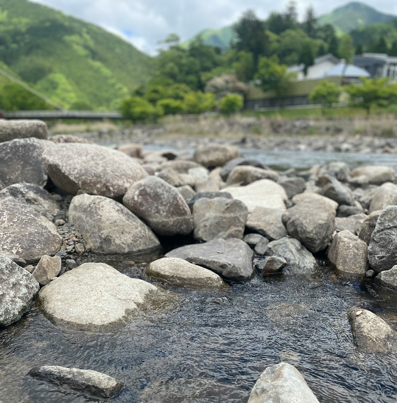 Gros plan sur des pierres de rivière et de l'eau qui coule avec des montagnes vertes en arrière-plan