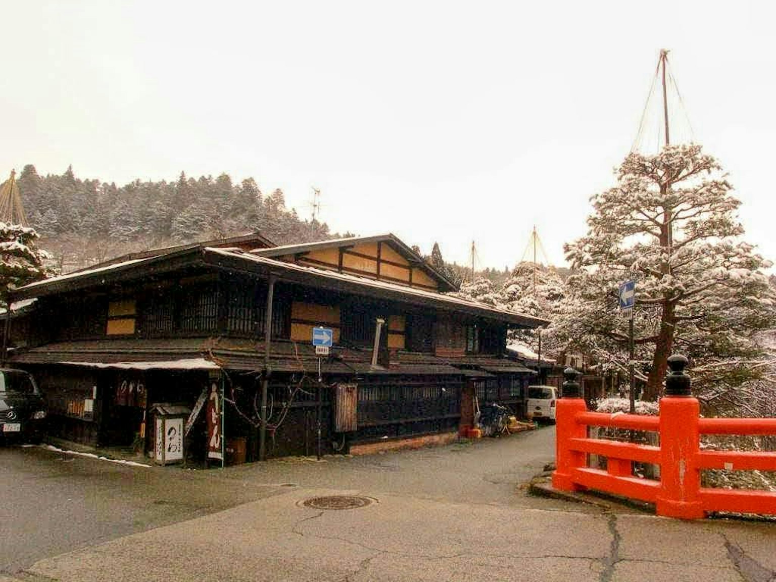 Casa japonesa tradicional cubierta de nieve con un puente rojo
