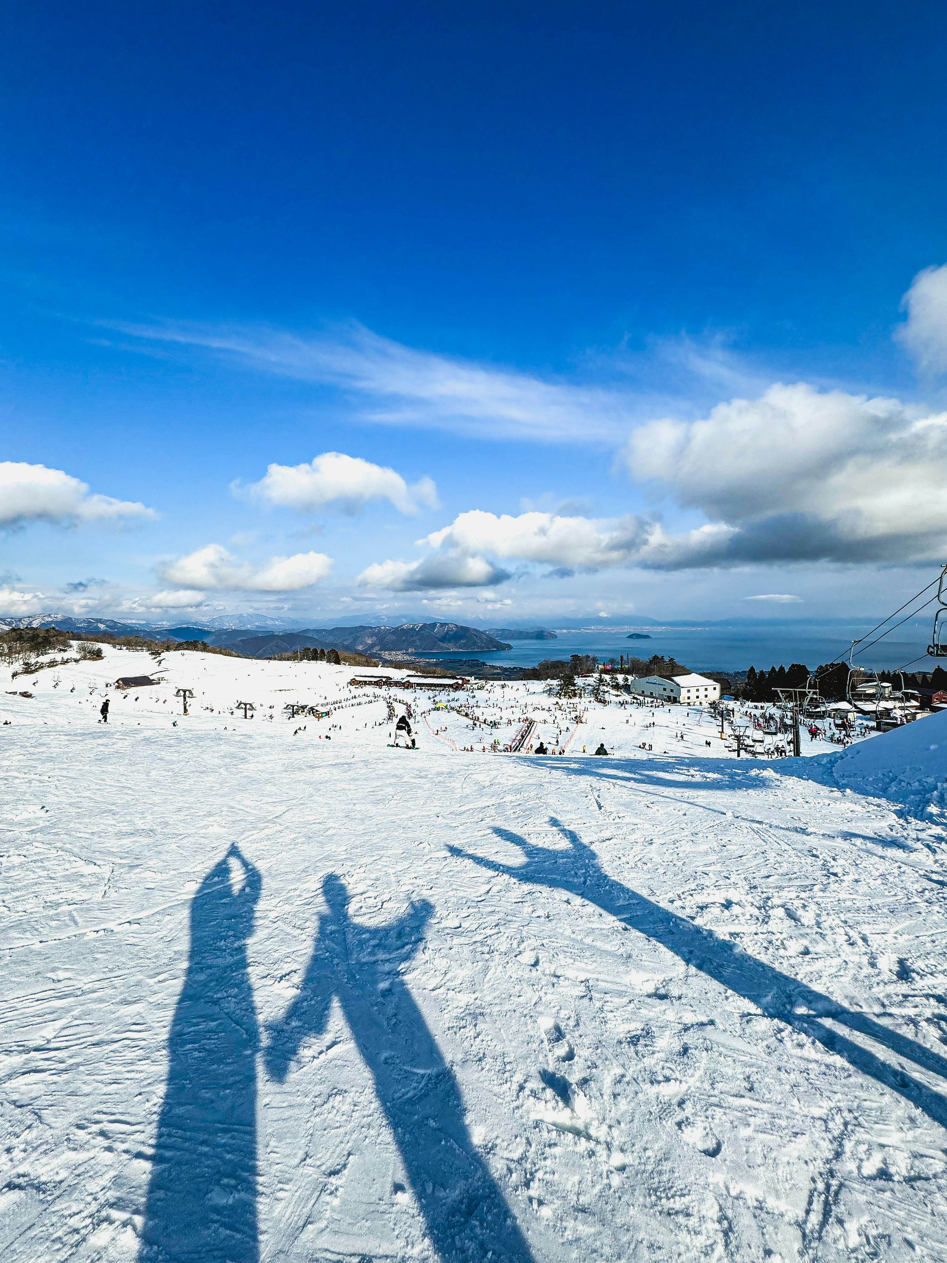 雪原の上に伸びる影と海沿いの山並み