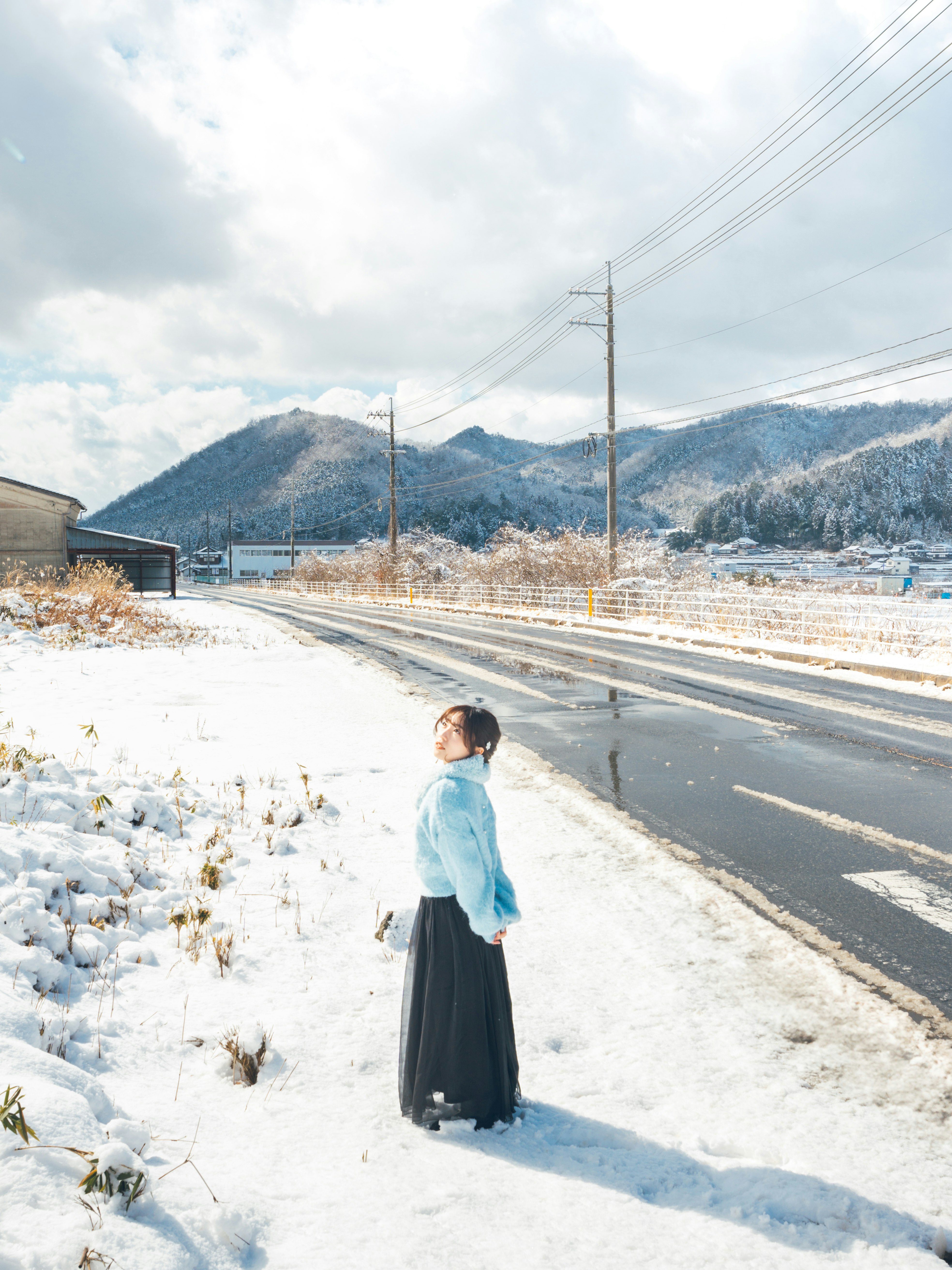 雪原の道を歩く女性と山並みの風景
