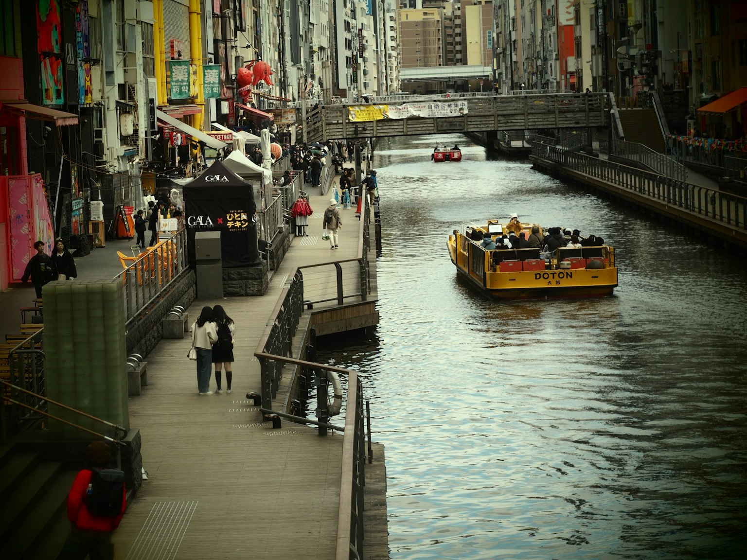 Promenade animée le long d'un canal avec un bateau de tourisme jaune