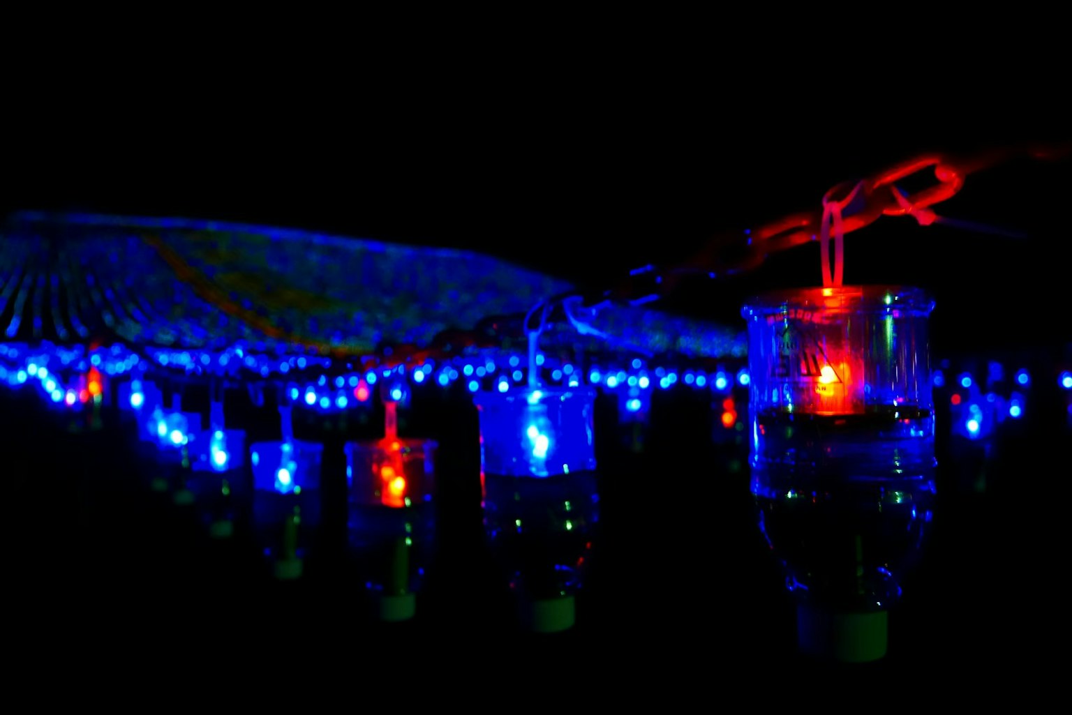 Una escena de botellas que emiten luces azules y rojas sobre un fondo oscuro