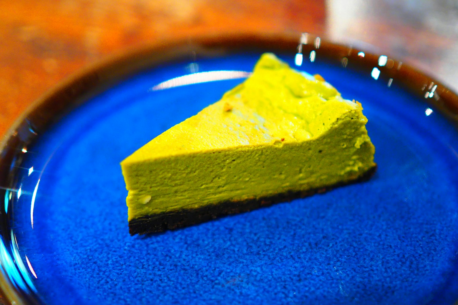 Stück Matcha-Kuchen auf einem lebhaften blauen Teller