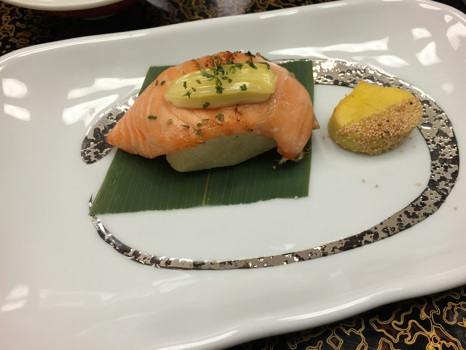 Sushi presentado de manera hermosa con salmón y aguacate sobre una hoja verde