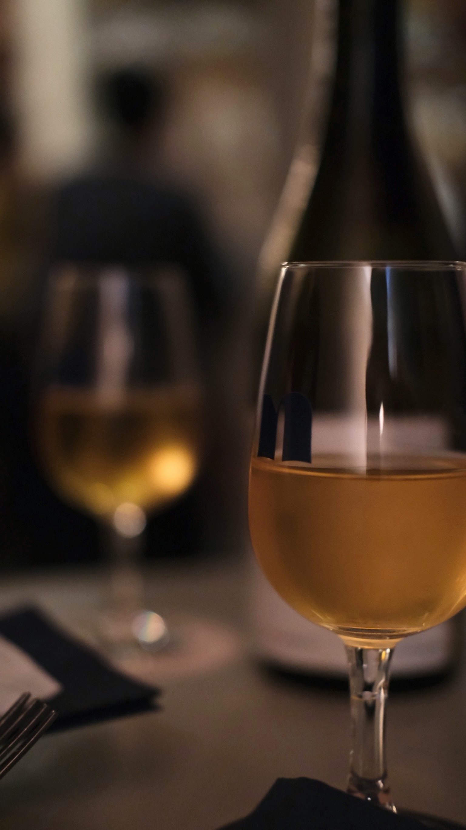 A glass of white wine on a table in a cozy restaurant setting