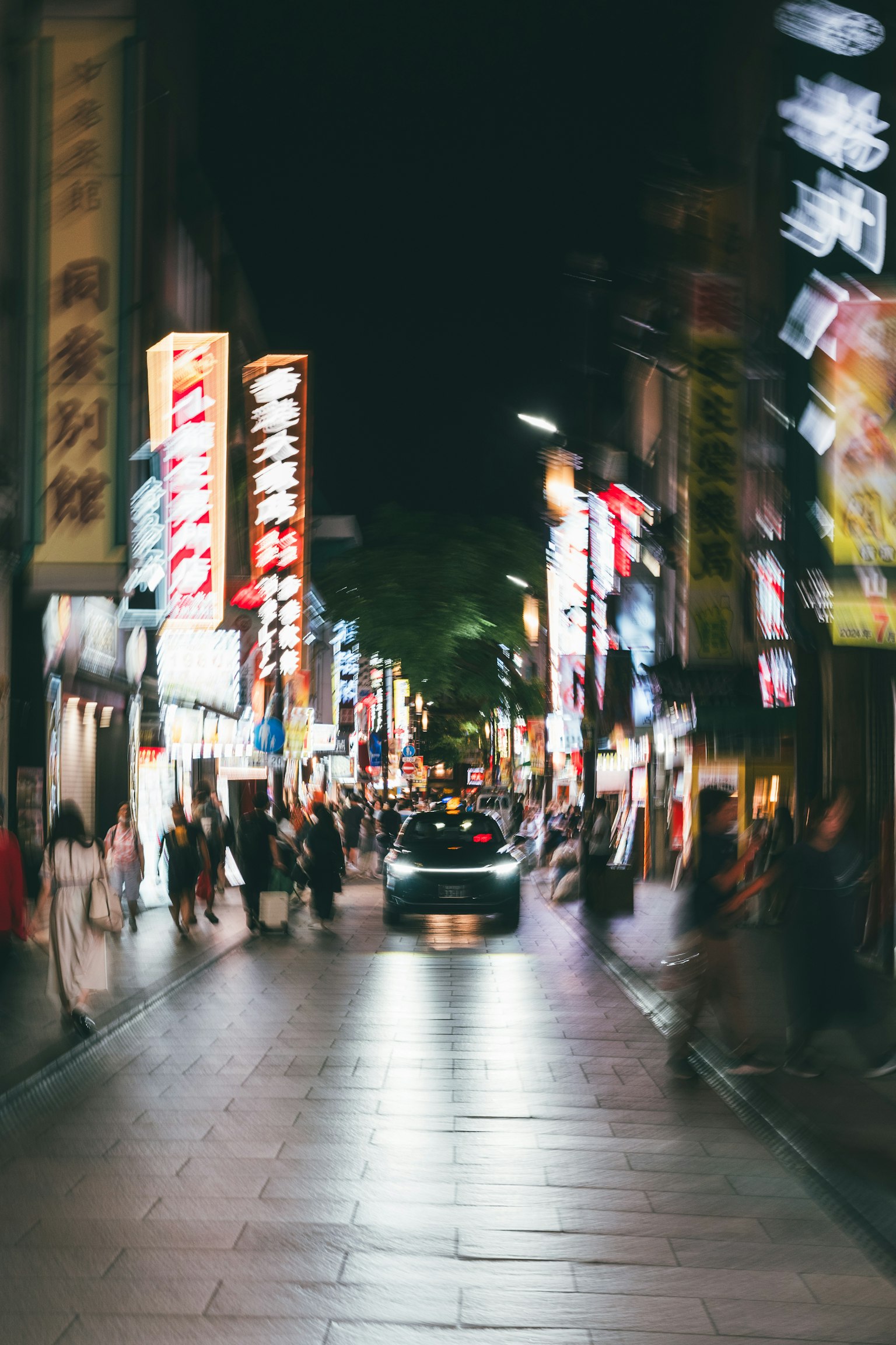 ภาพถนนที่เบลอในตอนกลางคืนพร้อมป้ายสว่างและรถยนต์