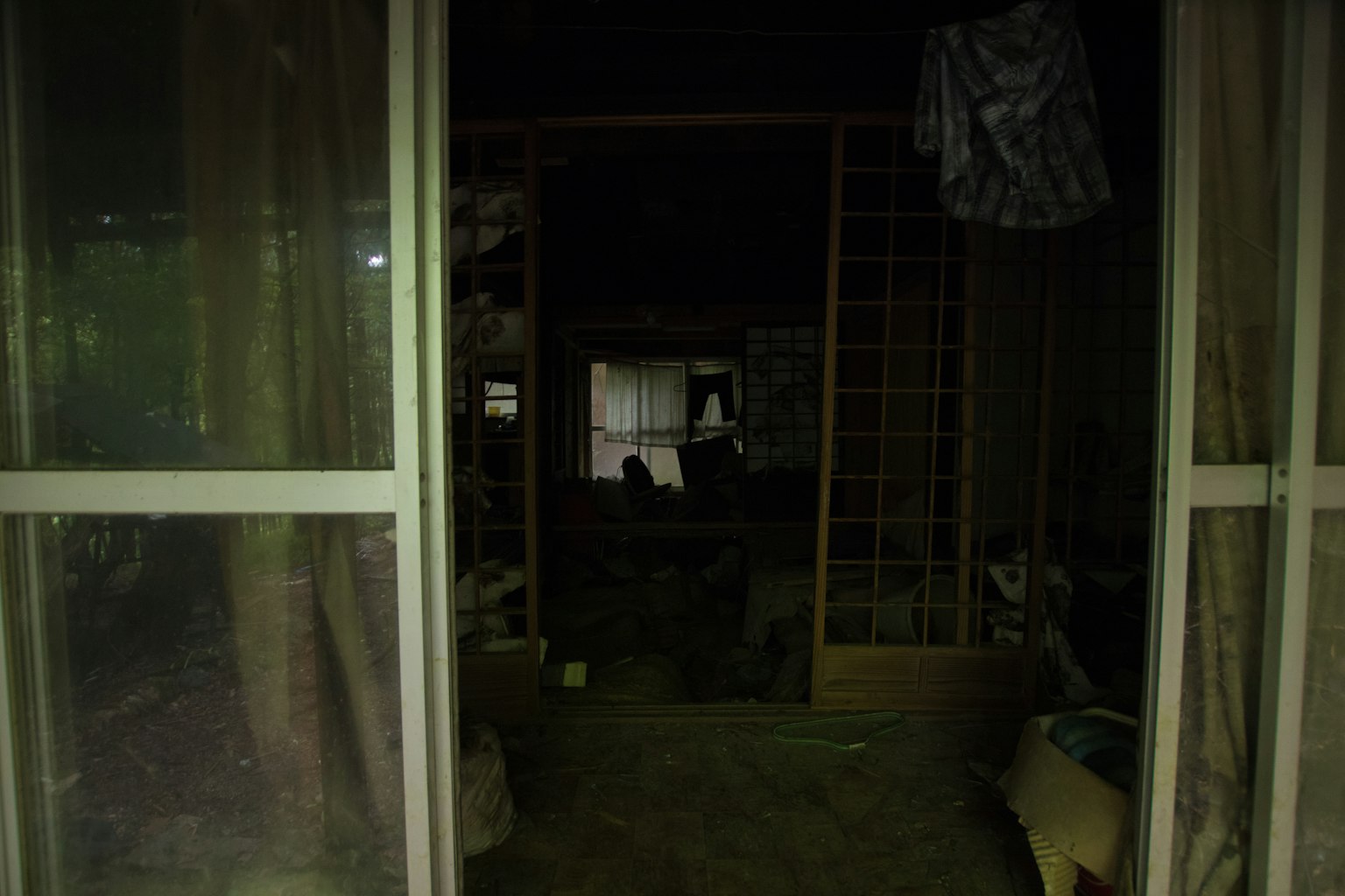 Porta aperta che conduce a una stanza debolmente illuminata con tende