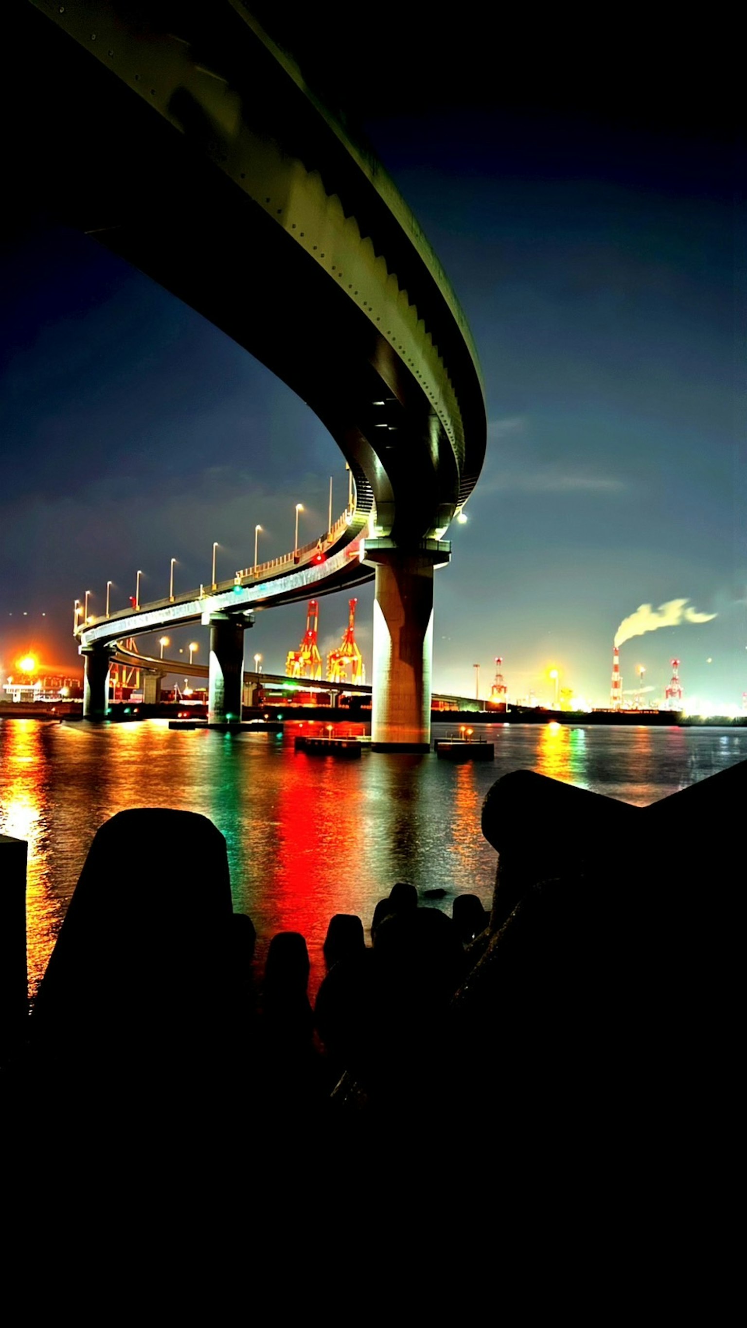 Night view of a bridge with colorful reflections on water