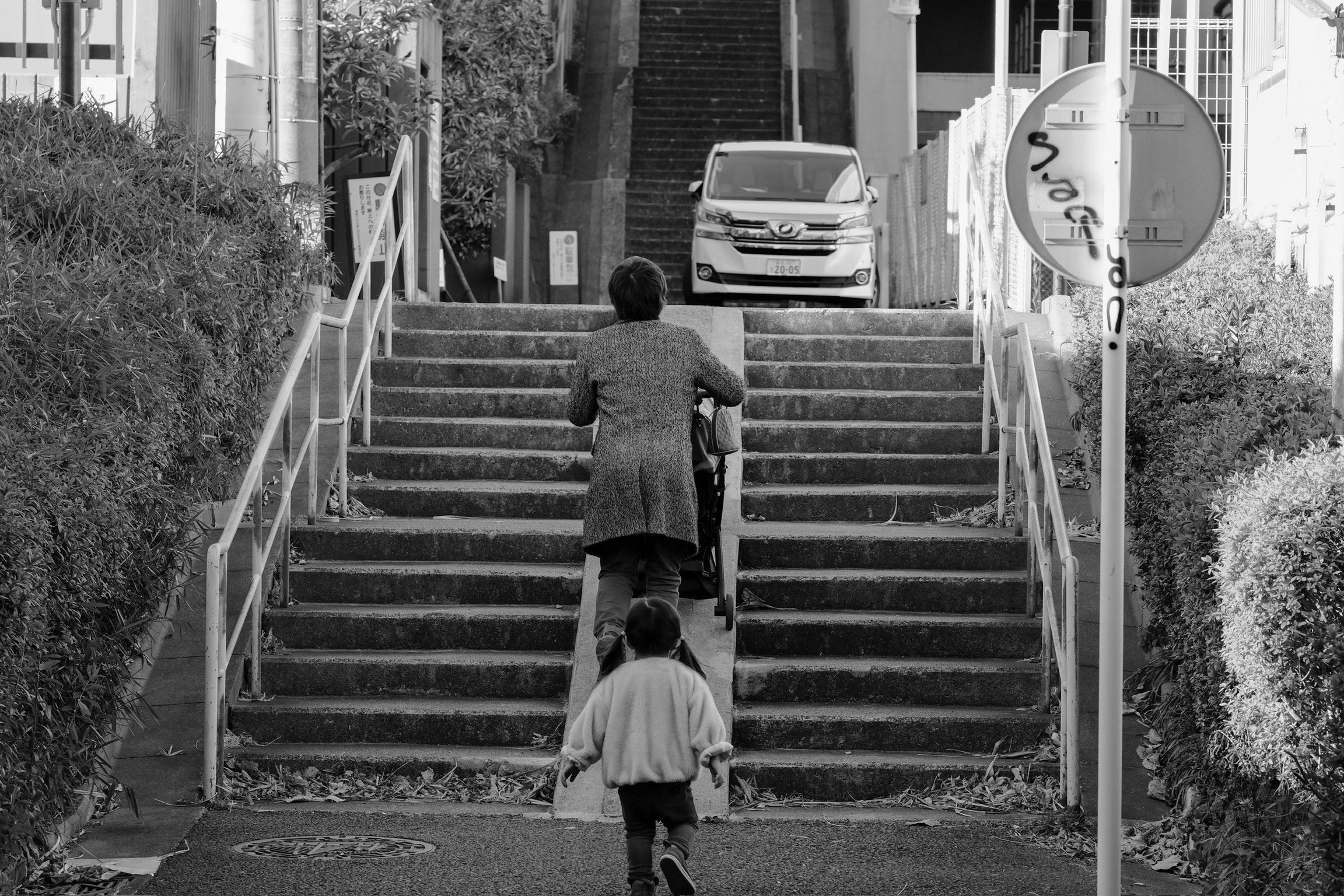 階段を上る親子の路地スナップ