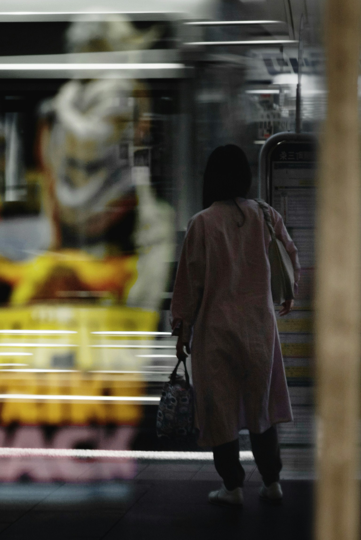 Seseorang menunggu kereta di stasiun dengan iklan kabur di latar belakang