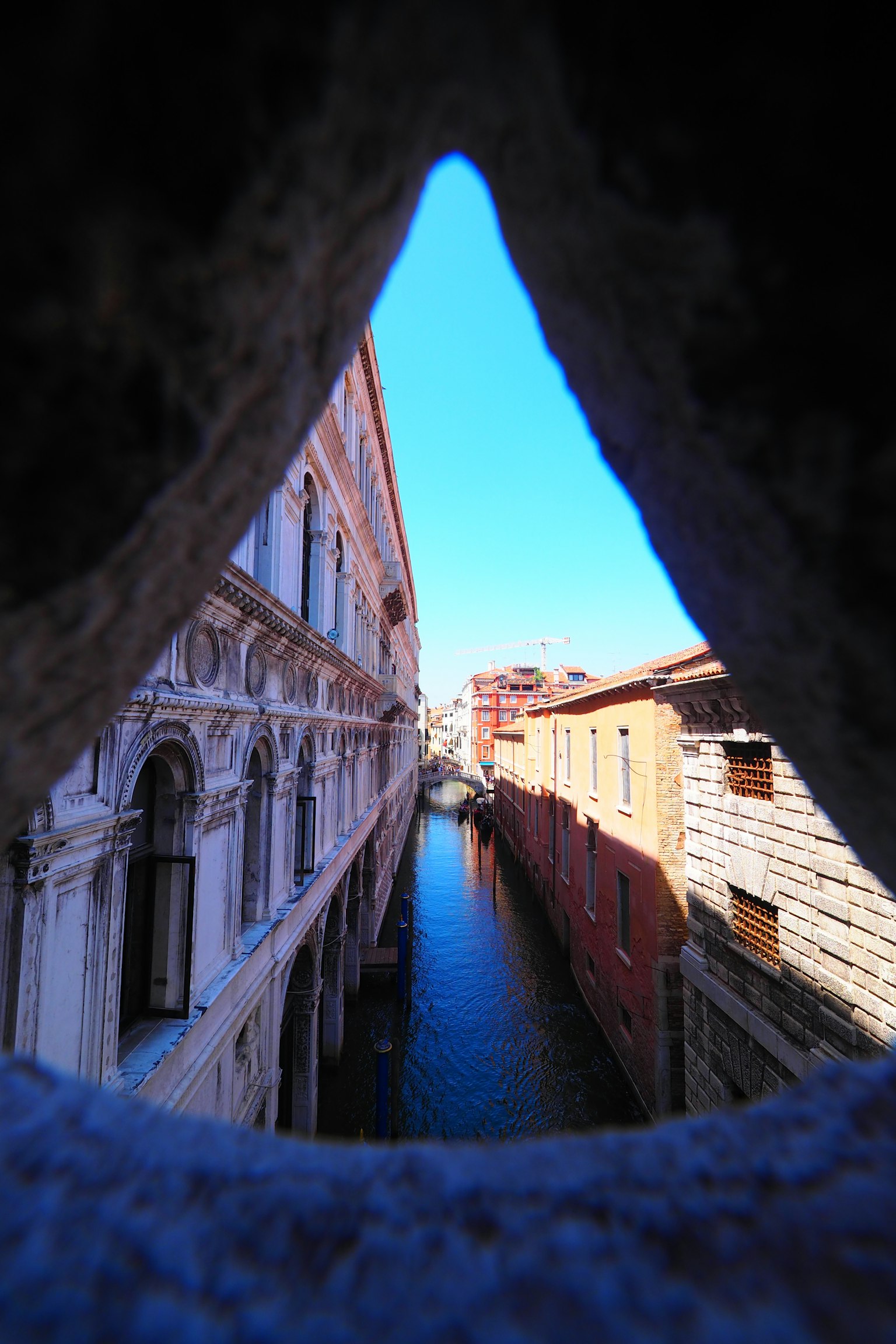Vista de un canal veneciano a través de una ventana de arco de piedra
