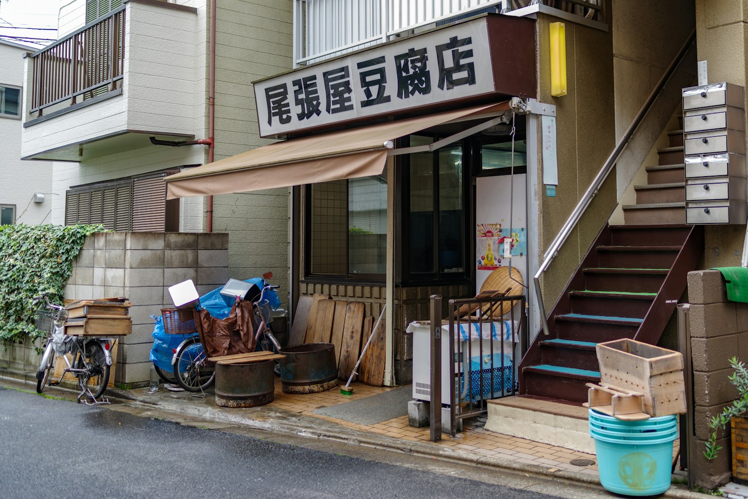 Exterior view of a shop with stairs bicycle and various items outside