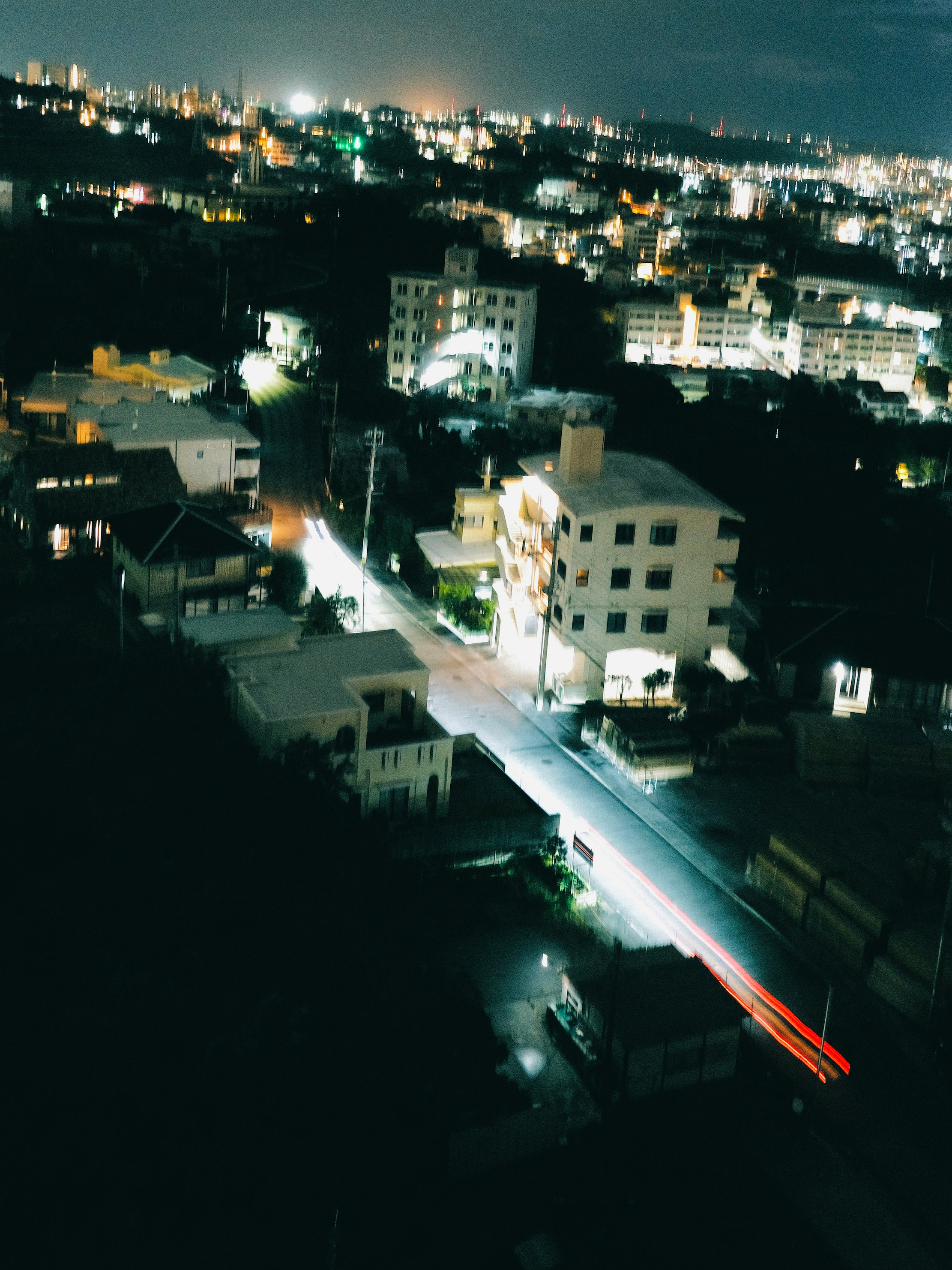夜の街並みと車のライトが流れる通り