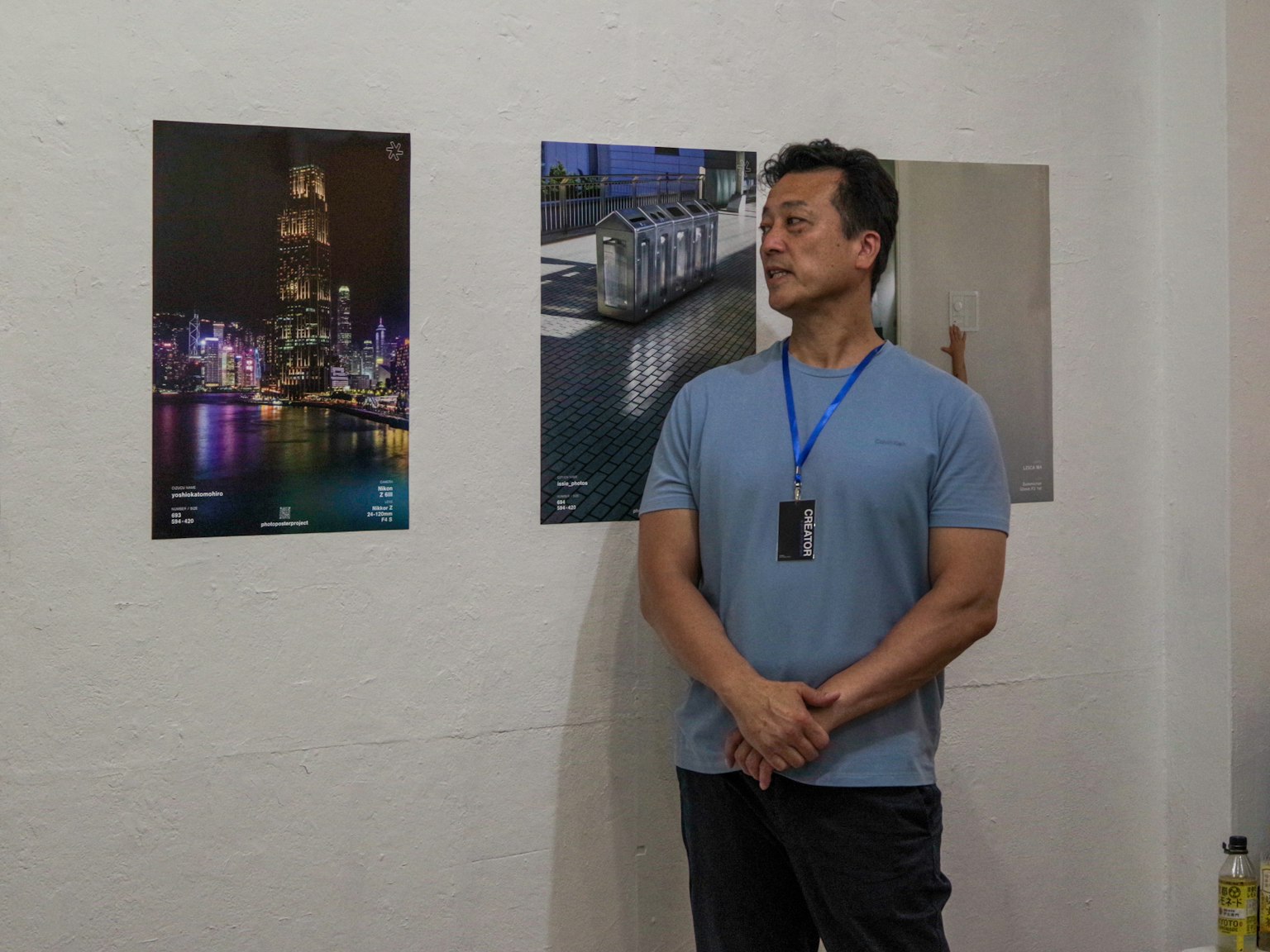 Un homme se tenant dans une galerie d'art à côté de photographies