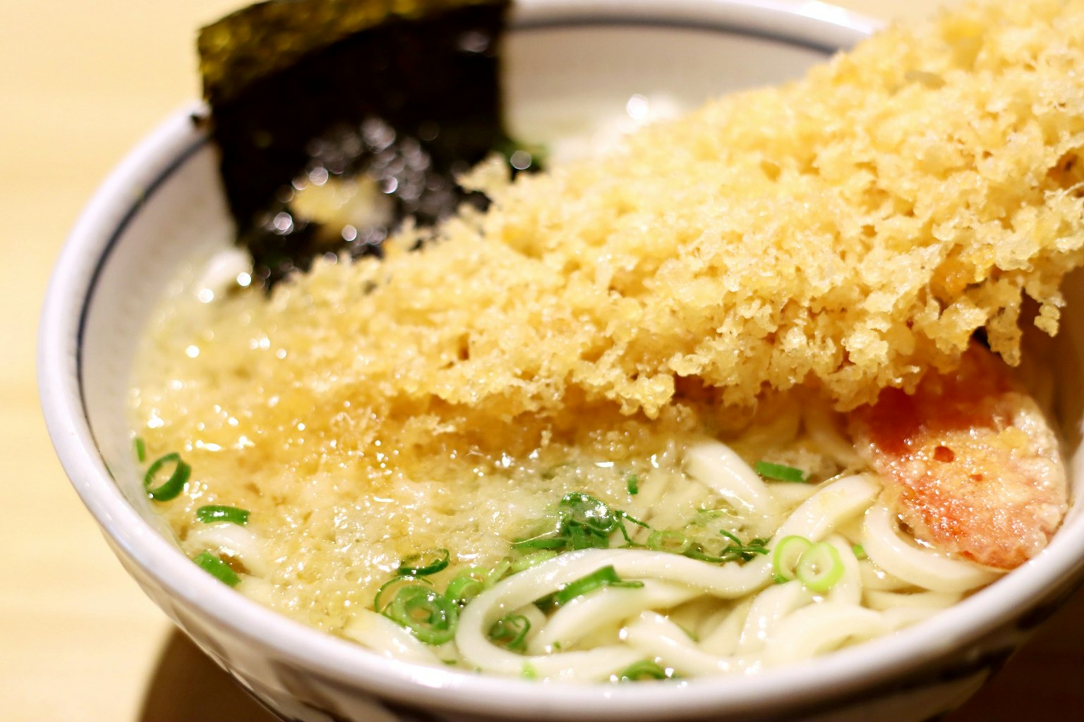 Schüssel mit Meeresfrüchte-Ramen, garniert mit knusprigen frittierten Elementen und Algen