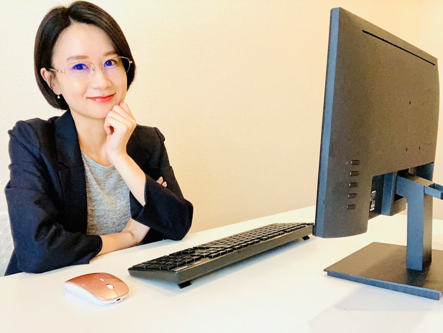 책상에 앉아 있는 여성, 검은 블레이저와 안경을 쓰고 생각에 잠긴 표정