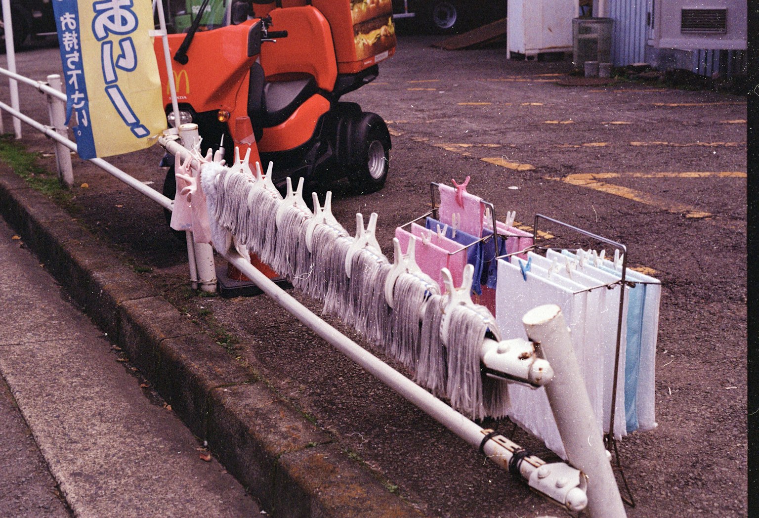 傘が並んでいる白い手すりとオレンジ色の小型トラクターの画像