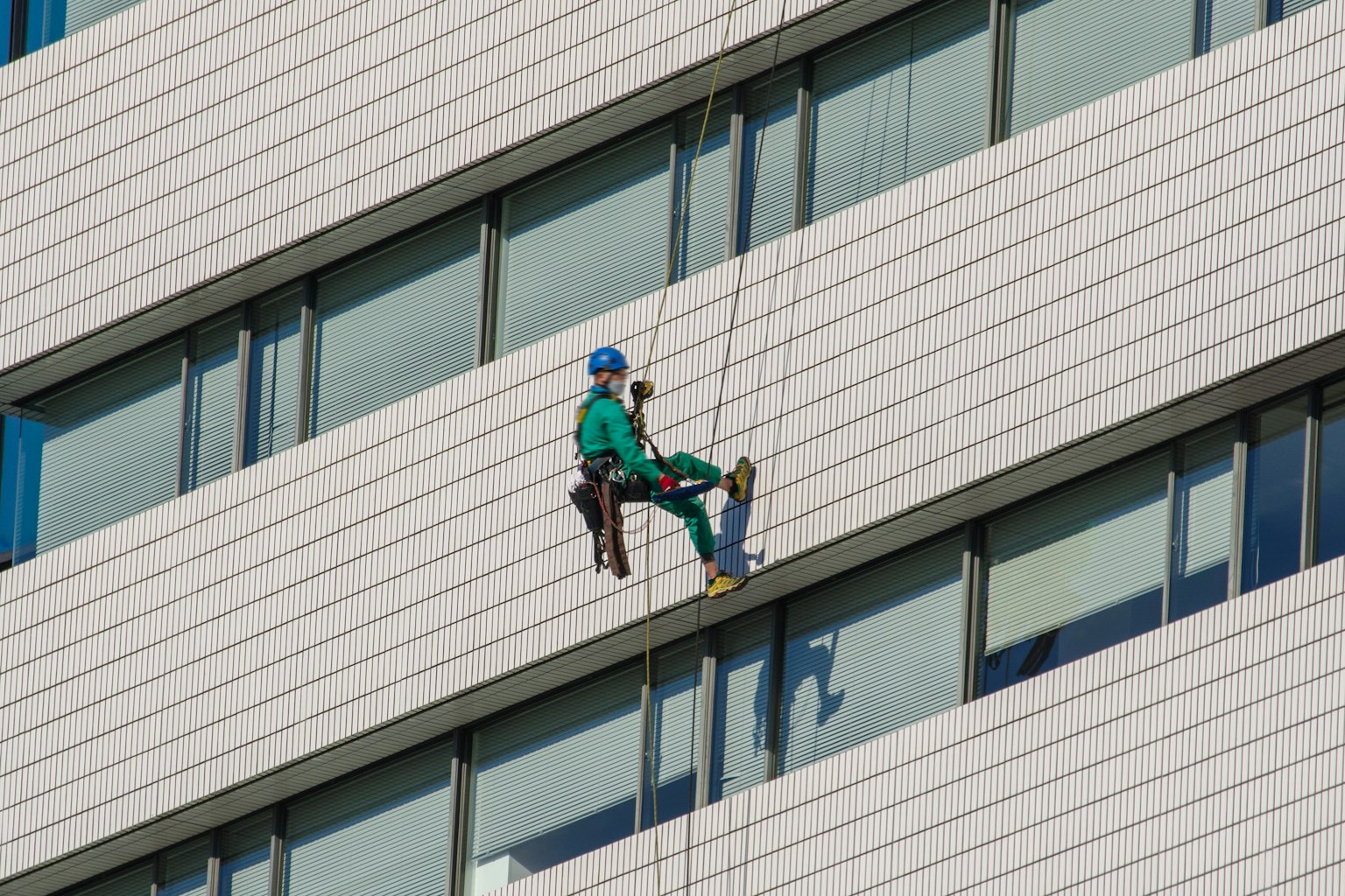 Travailleur suspendu par des cordes nettoyant l'extérieur d'un bâtiment