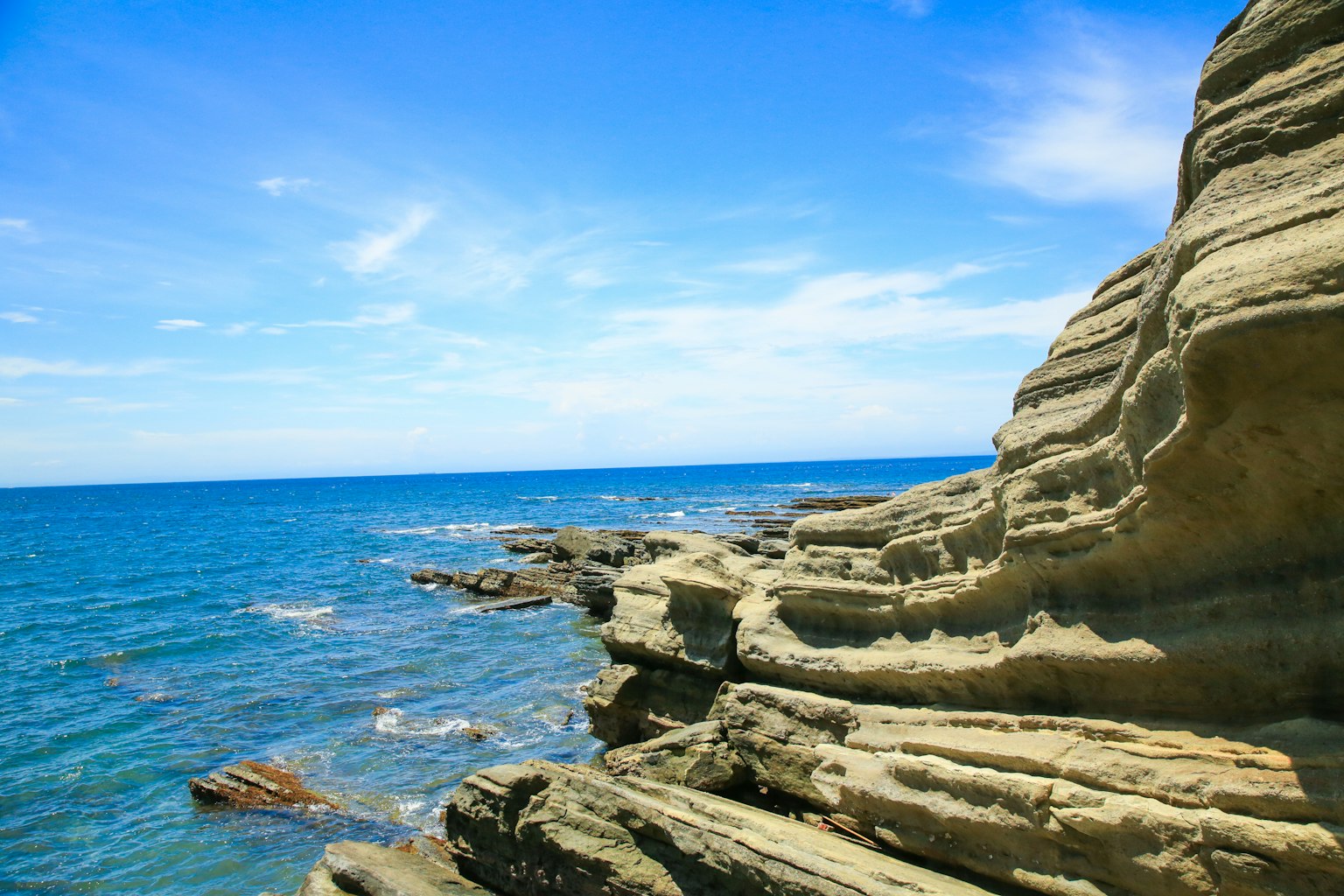 蓝色海洋和岩石海岸的景色在明亮的天空下