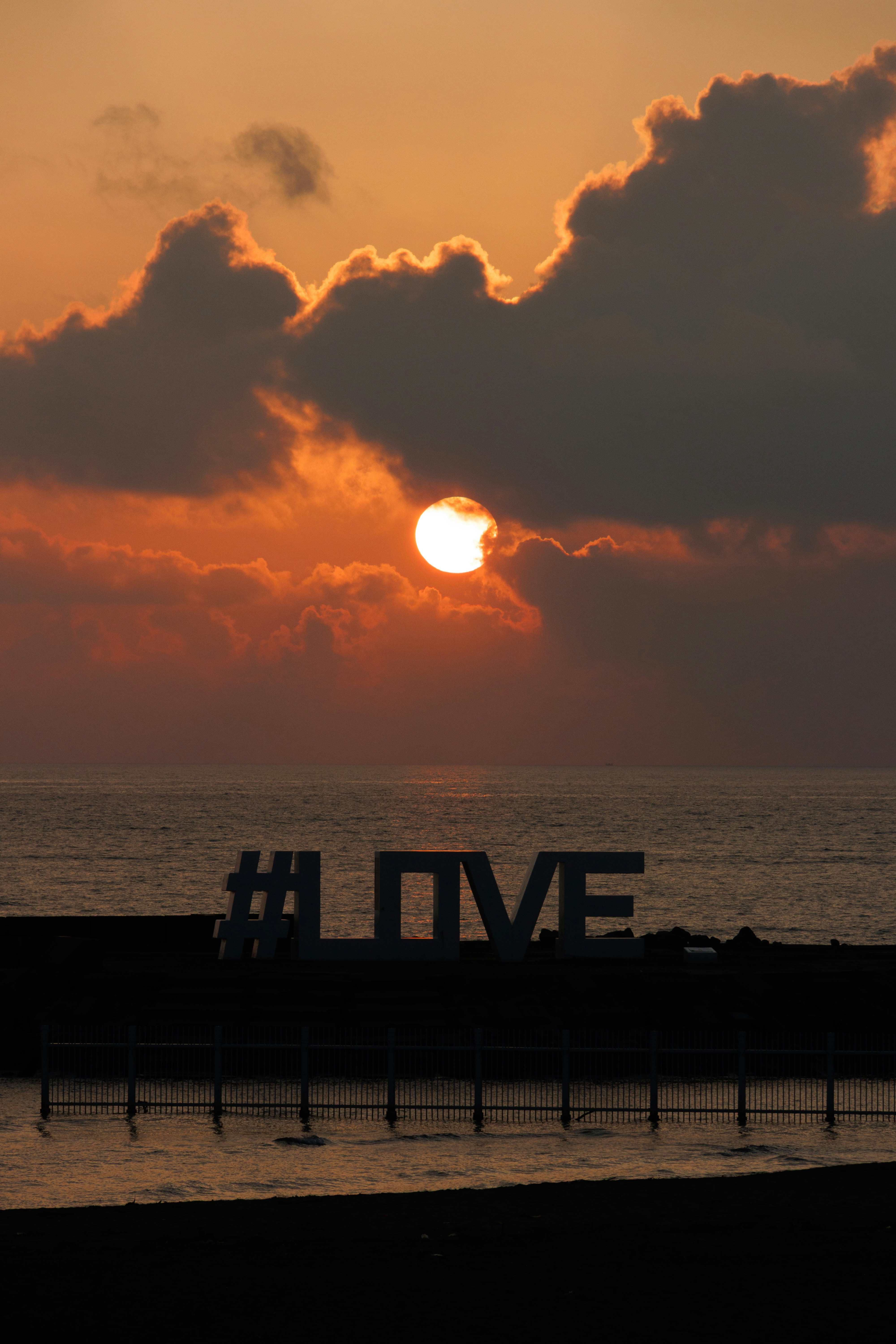 夕日に照らされた海辺の桟橋と「#LOVE」文字