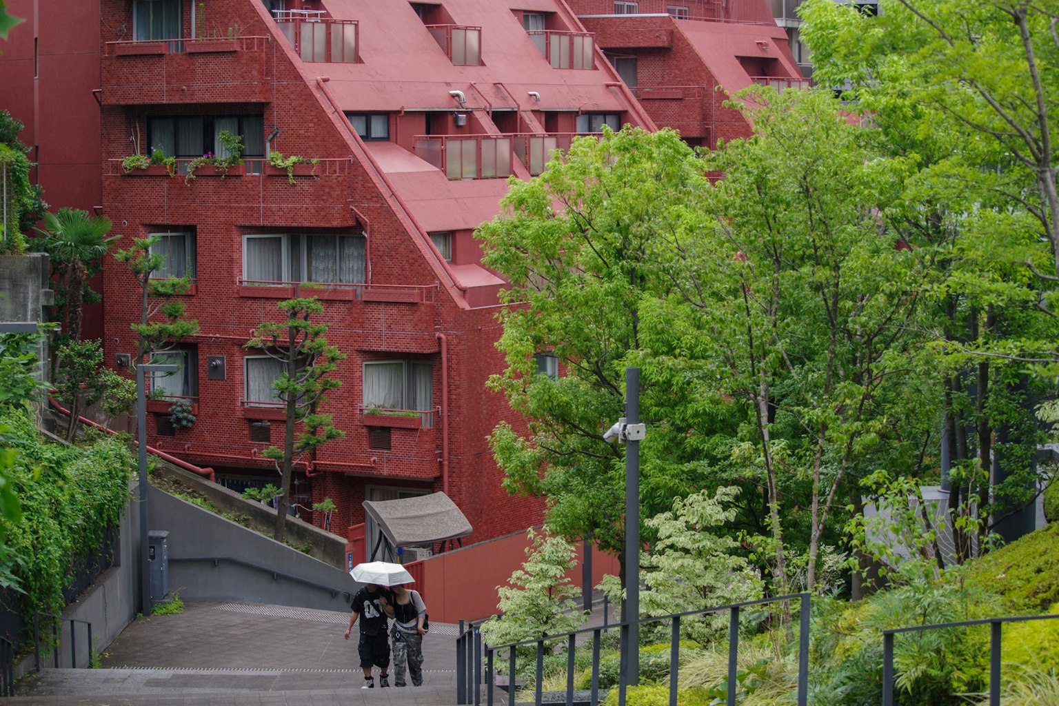 Un bâtiment moderne rouge entouré d'arbres verts luxuriants