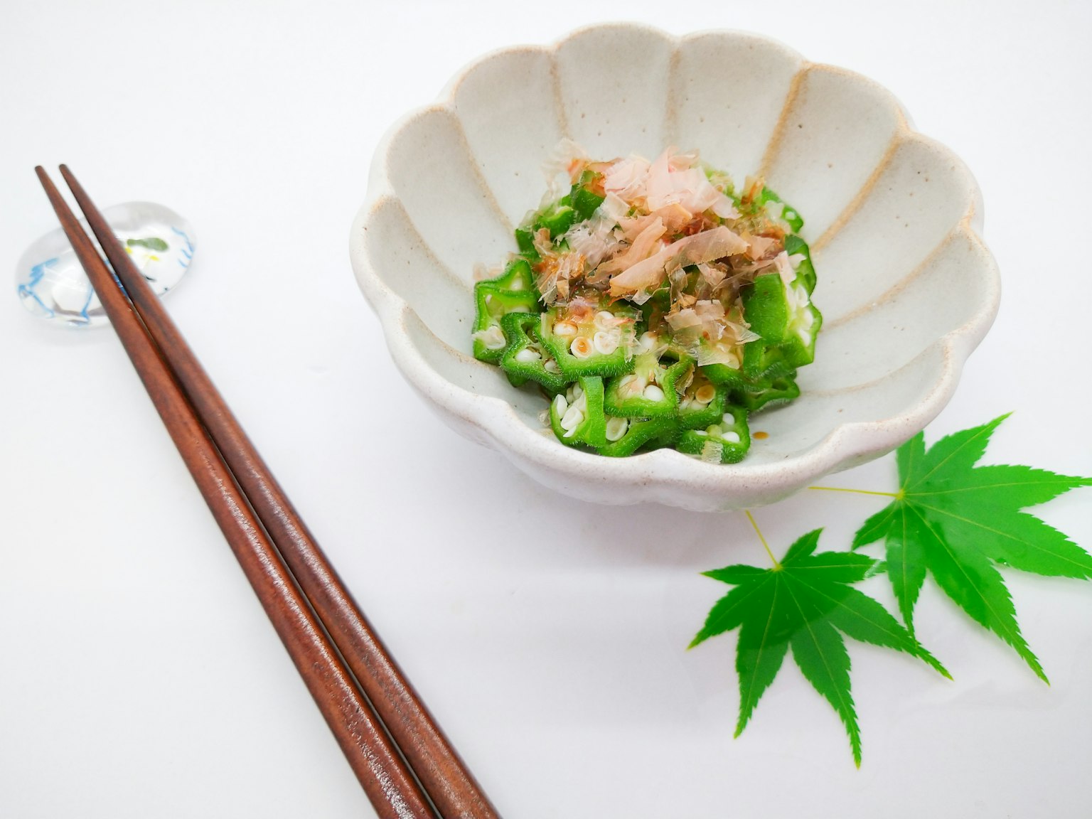 Insalata di okra guarnita con scaglie di bonito in un piatto bianco