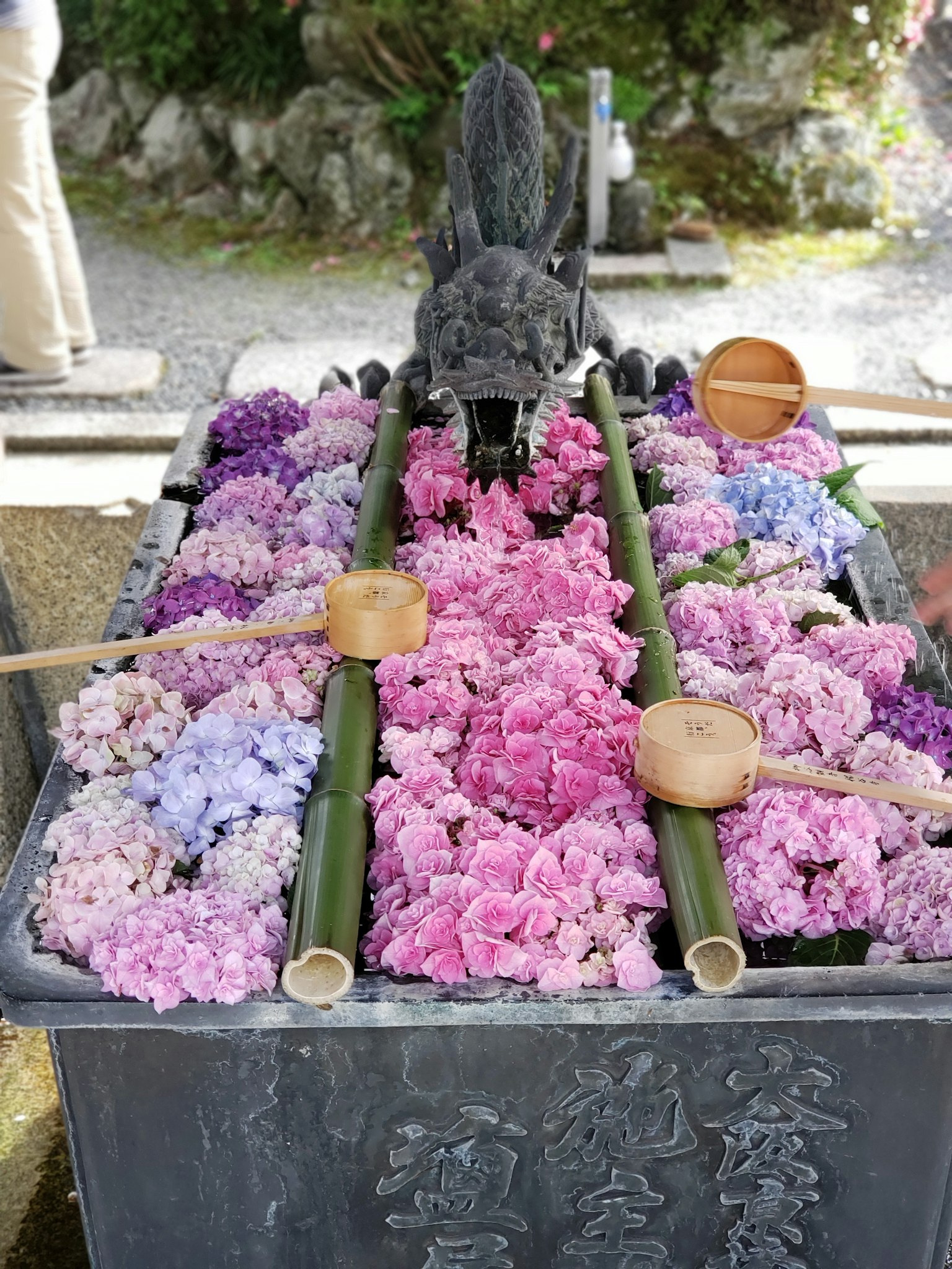 一個裝滿五彩花朵和竹棒的石盆