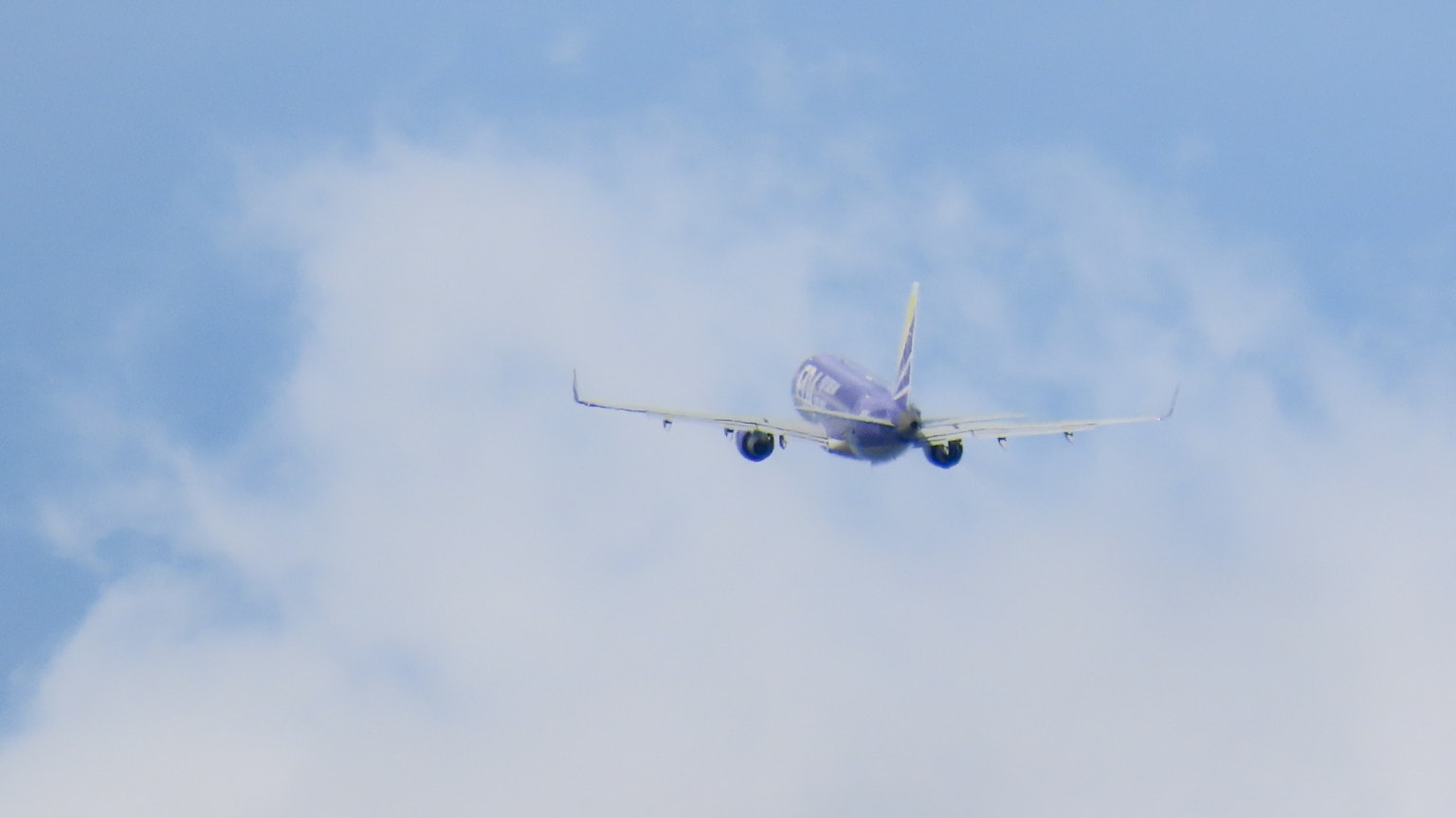 Flugzeug fliegt gegen einen blauen Himmel mit Wolken
