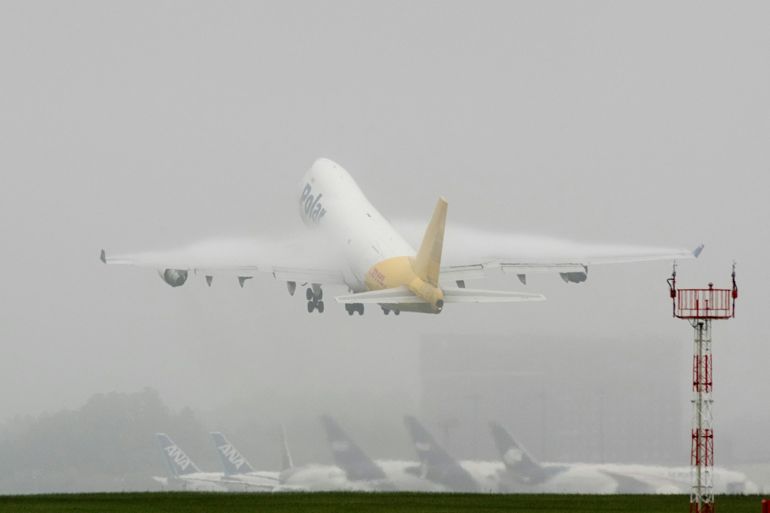 Gran avión de carga despegando en la niebla con la pista del aeropuerto al fondo