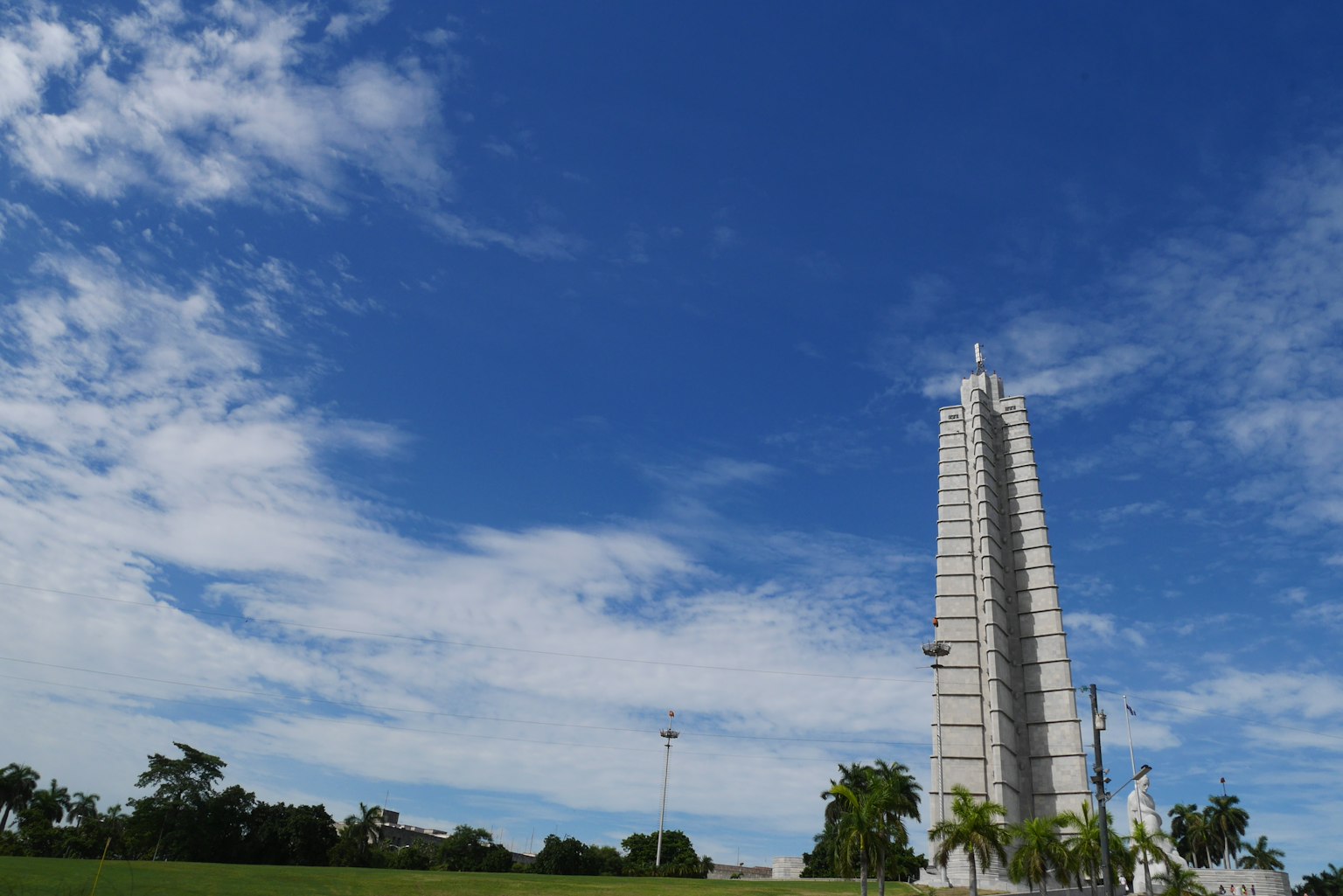 Hoher Turm unter blauem Himmel mit weißen Wolken und grünem Gras