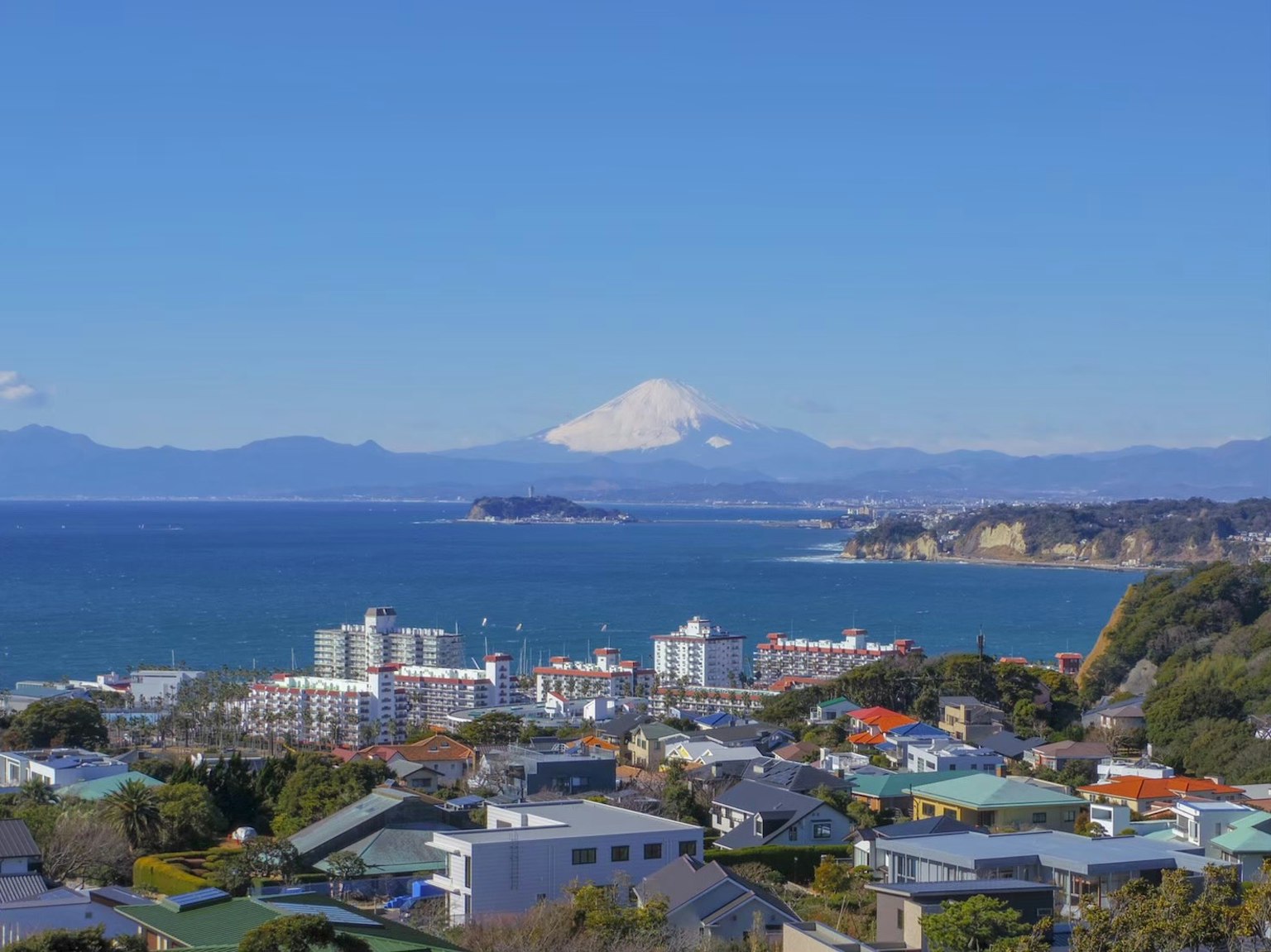 Vista panoramica dell'oceano e delle montagne con il monte Fuji in lontananza