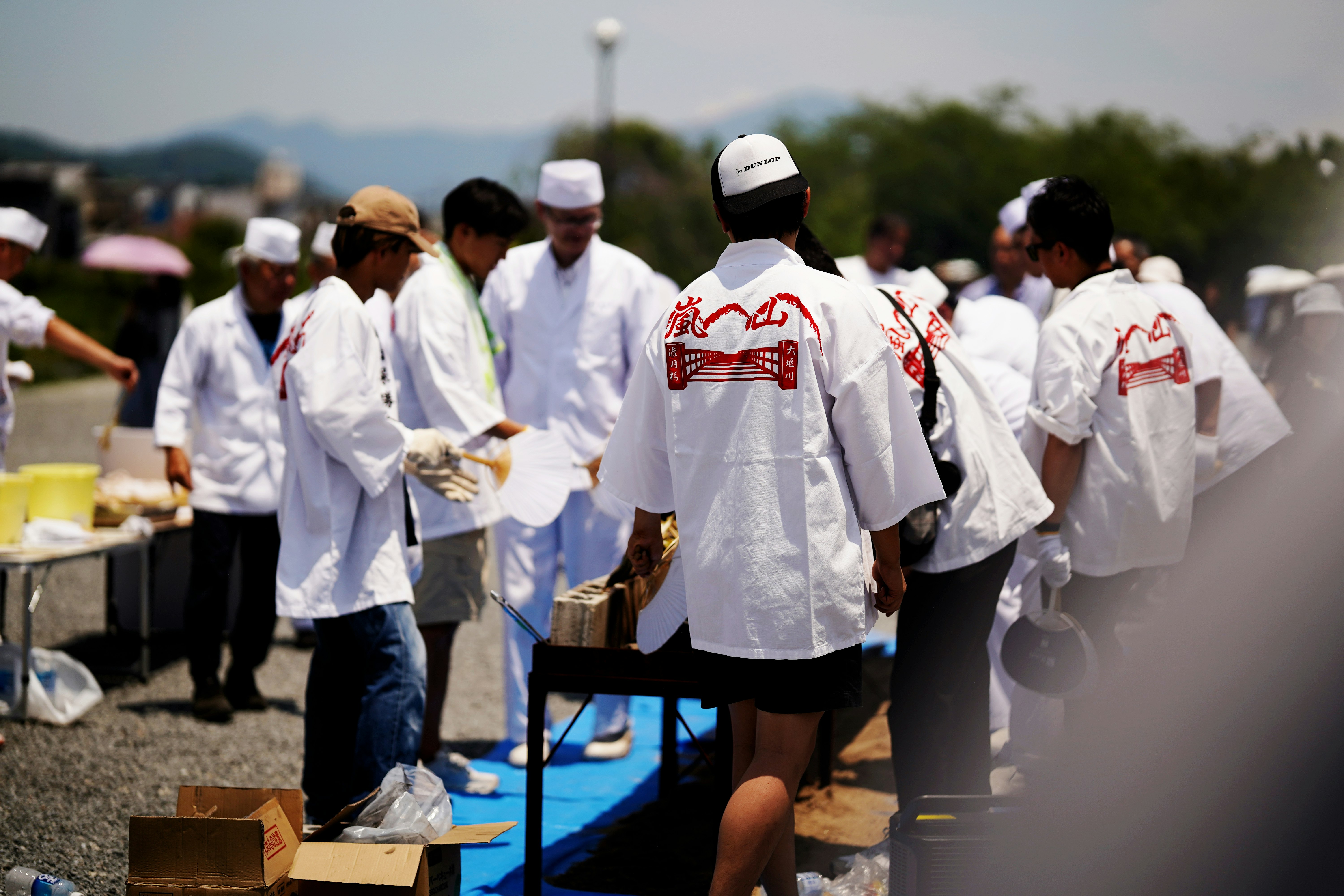 嵐山若鮎祭の白い衣装を着た人々が並ぶ屋外会場の風景