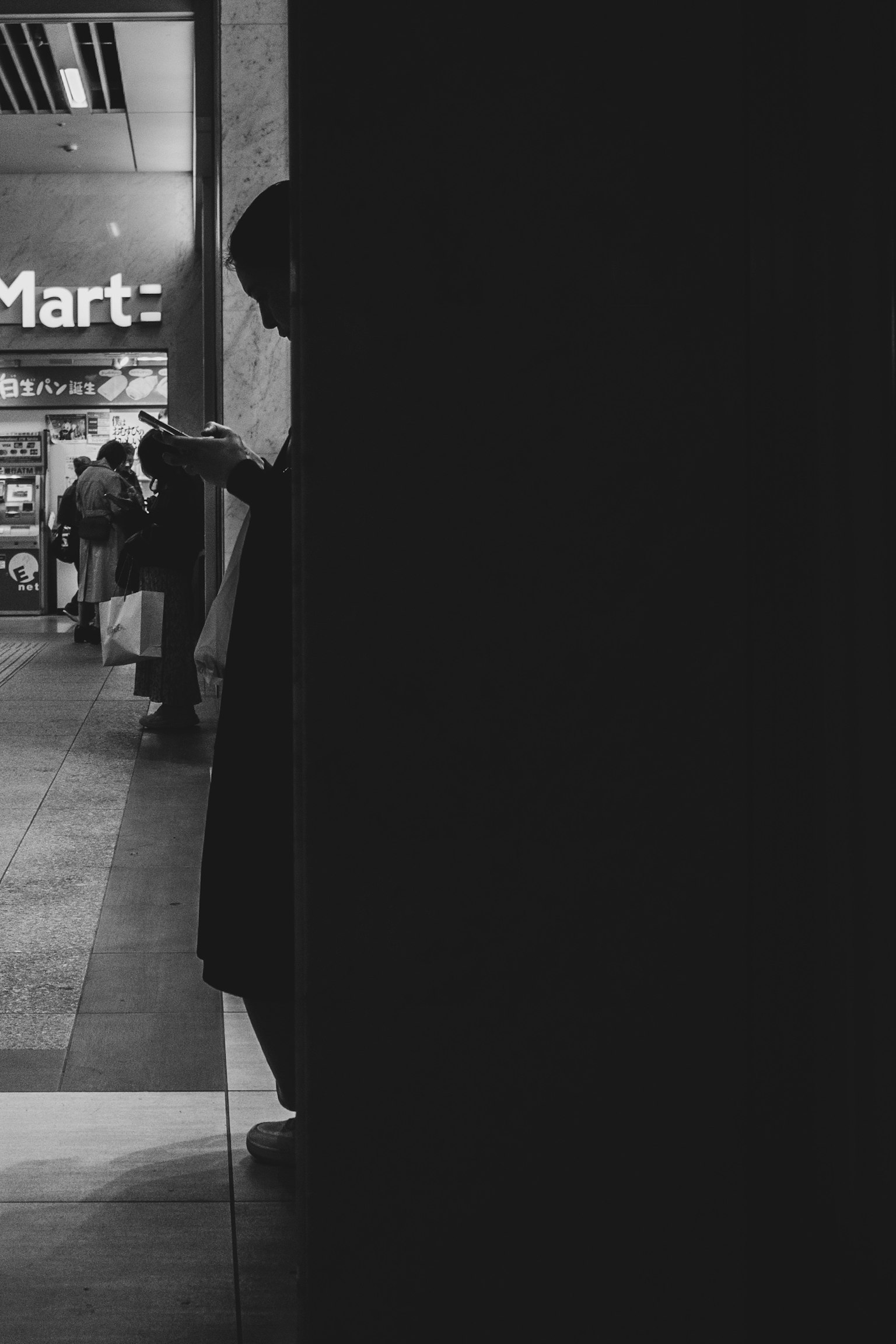 Silhouette d'une personne se tenant contre un fond sombre avec un panneau de marché lumineux