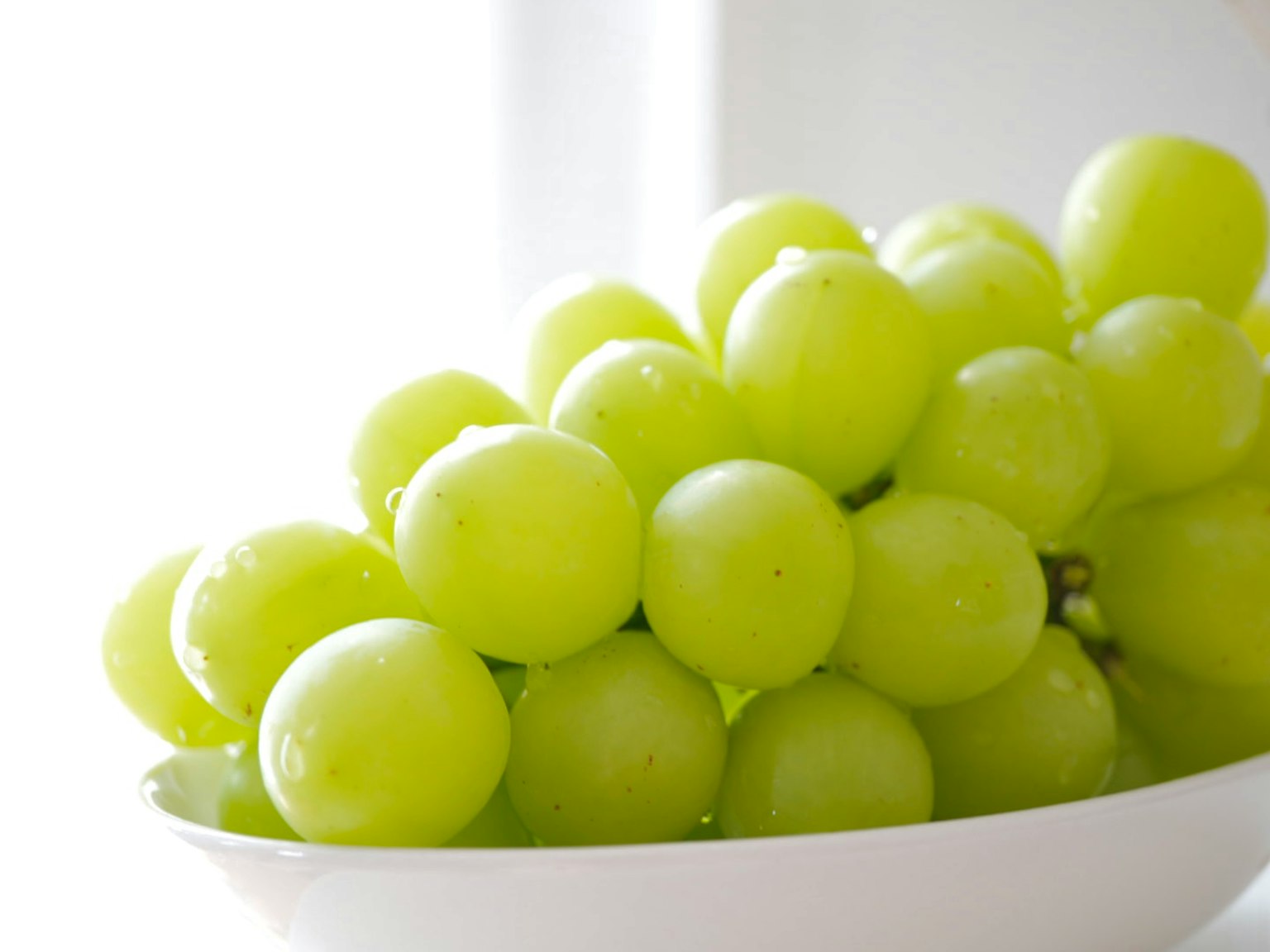 Uva verde fresca raggruppata in una ciotola bianca