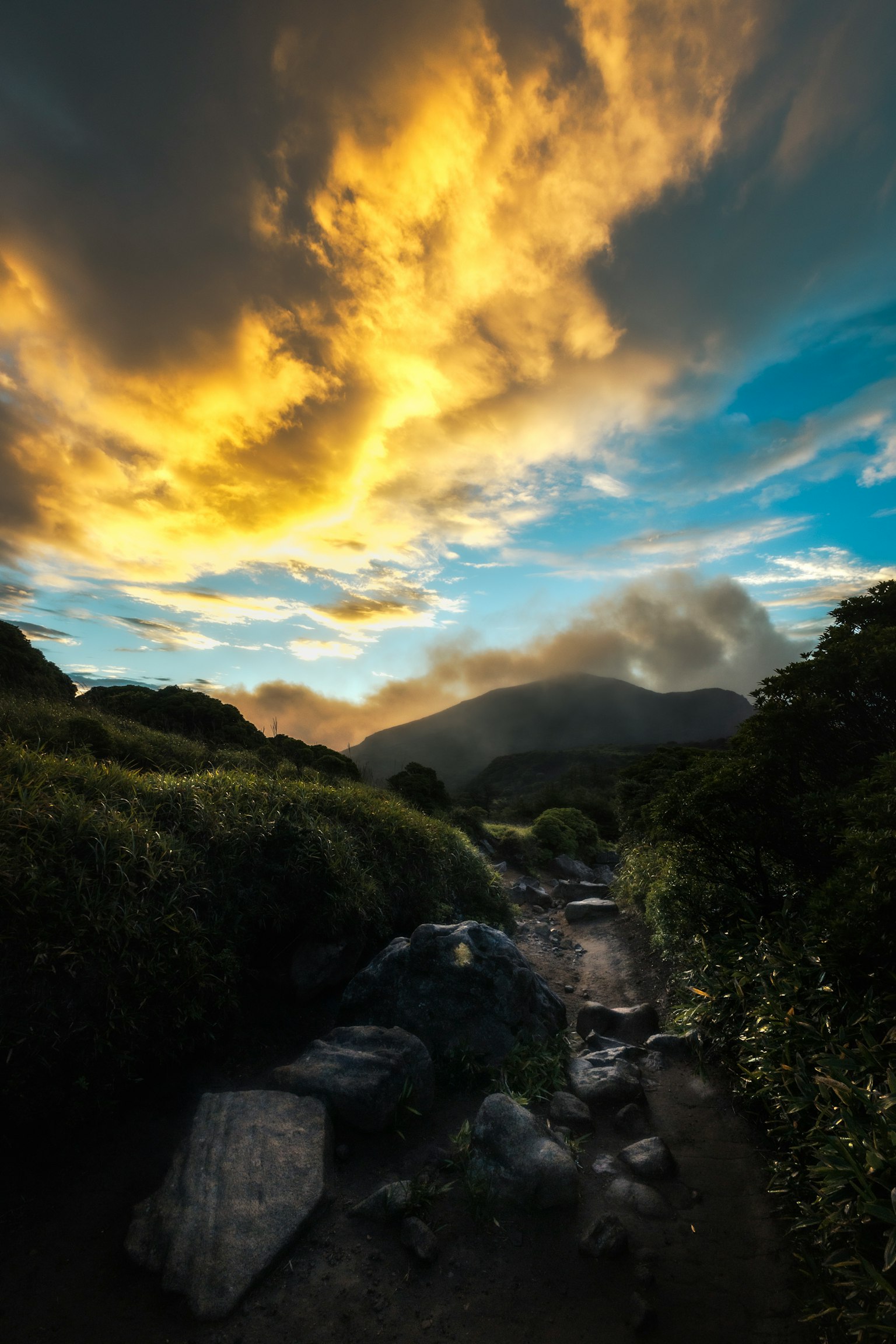 日落天空與山脈和郁郁蔥蔥的綠地的風景