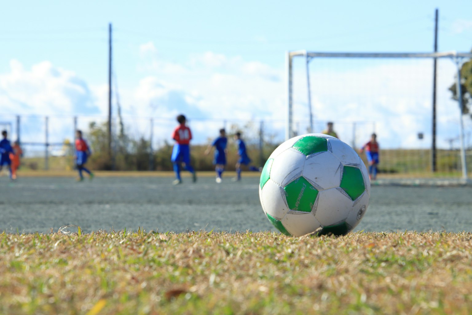 Lapangan sepak bola dengan bola sepak berpolakan hijau dan pemain