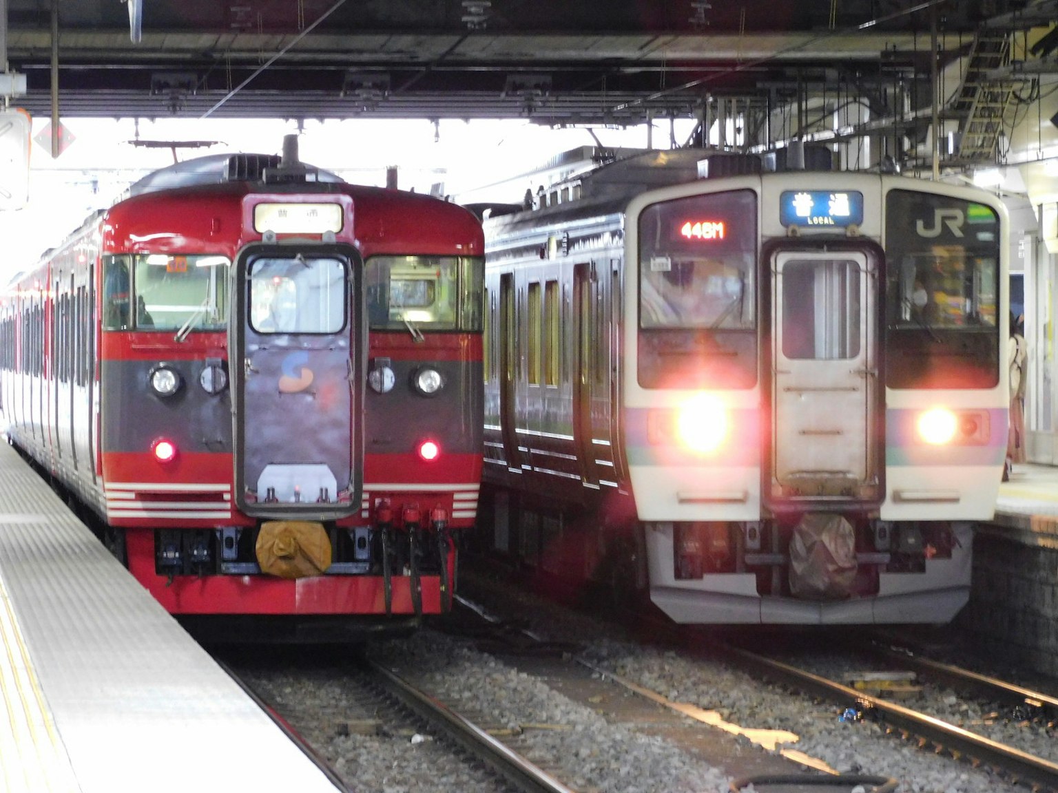 รถไฟสีแดงและสีขาวอยู่ข้างกันที่สถานีรถไฟ