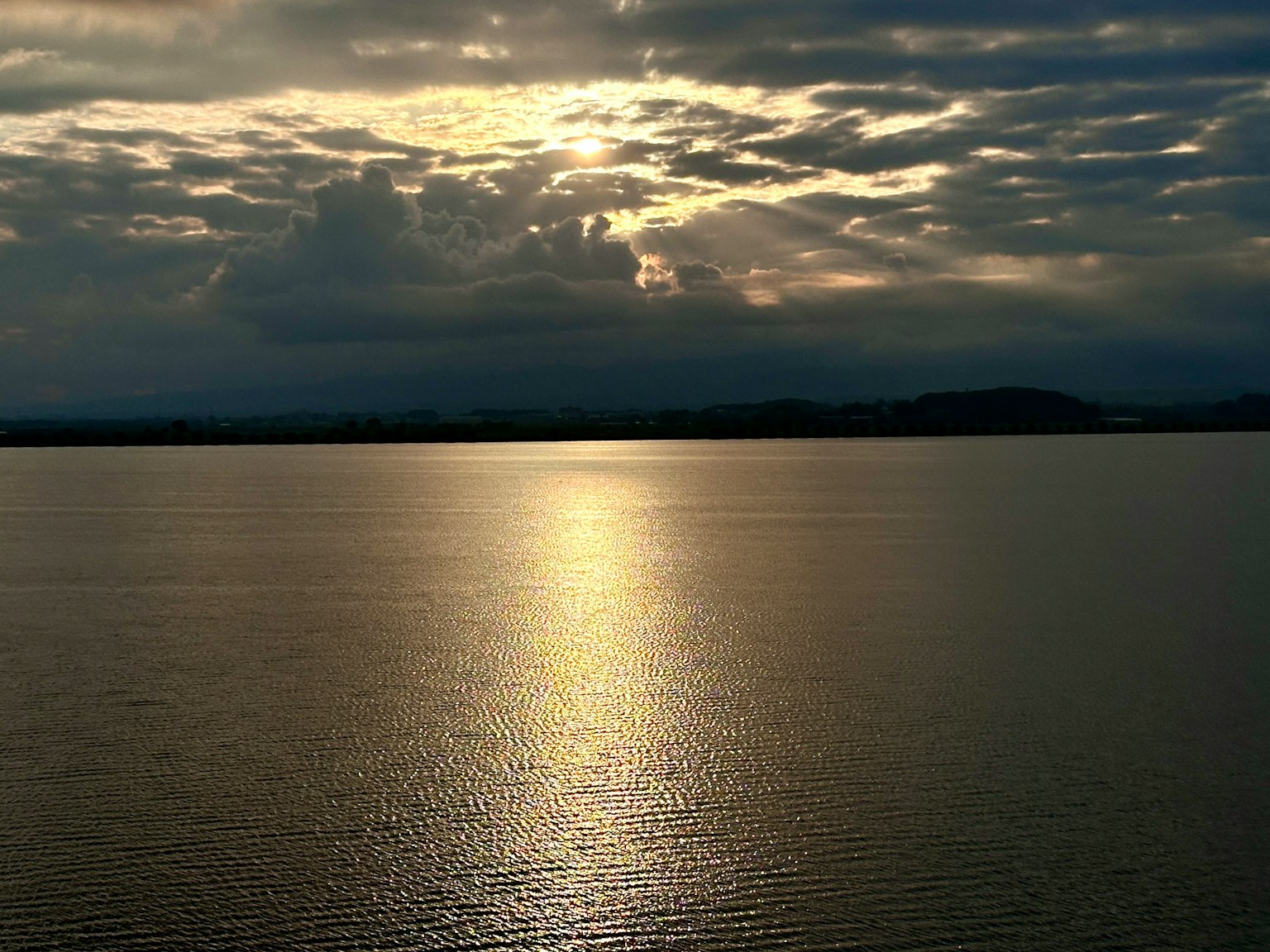 Tranquil water surface reflecting sunset light and clouds