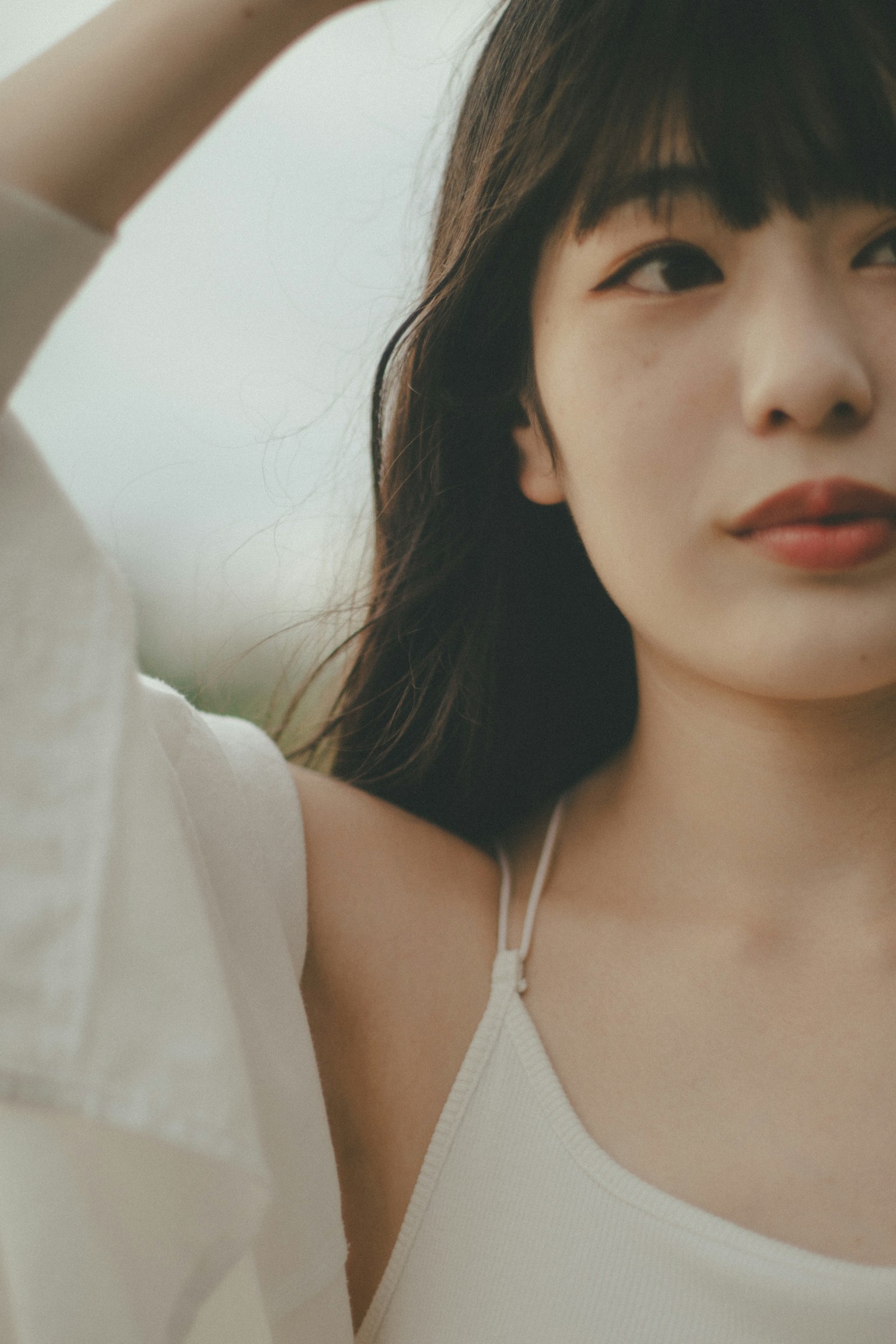 Gros plan d'une femme en tenue blanche avec un éclairage naturel doux et un arrière-plan flou