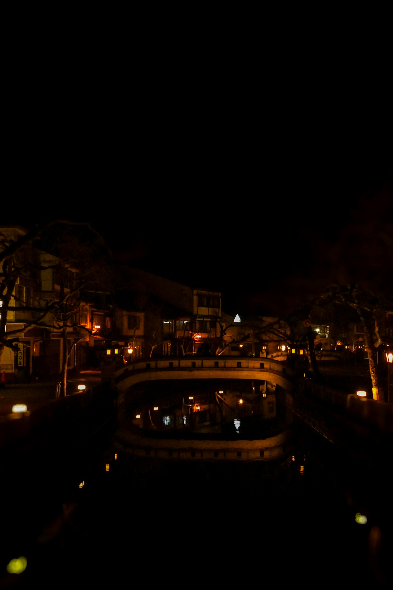 Une scène nocturne sereine avec un pont illuminé par des lumières chaudes sur un canal calme