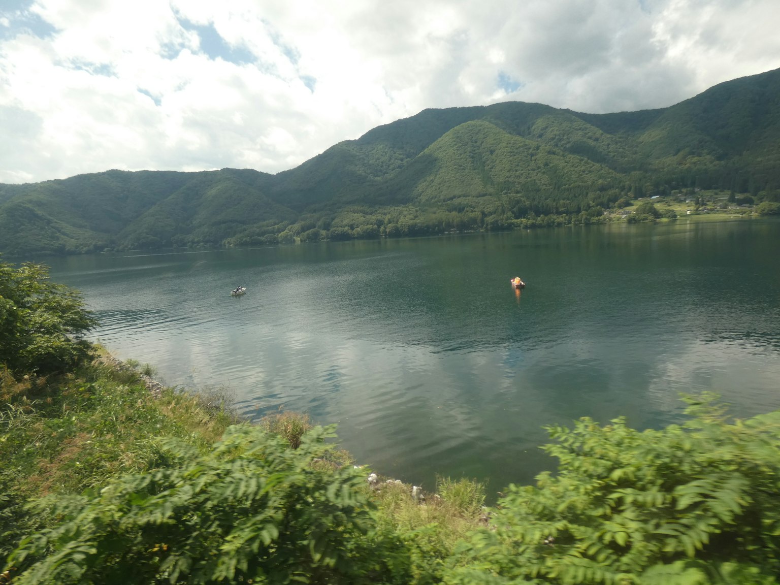 Ruhiger See mit üppigen grünen Bergen im Hintergrund