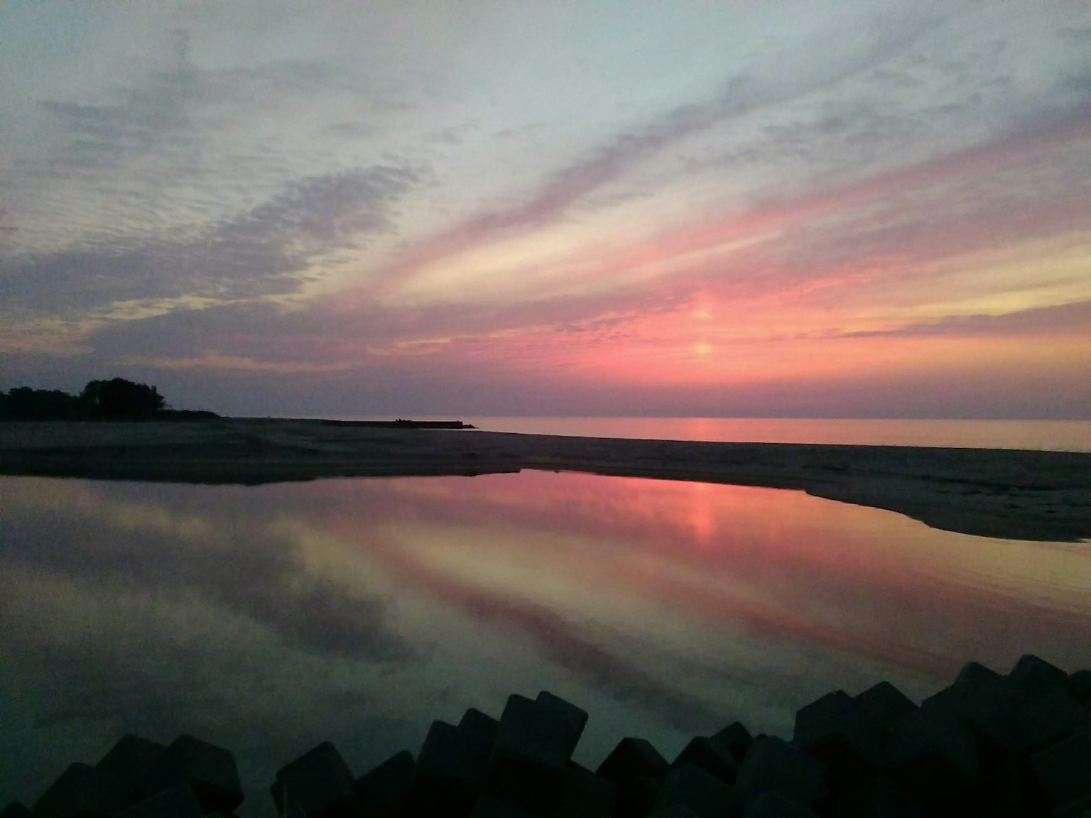 Bellissimo tramonto che si riflette sul mare superficie d'acqua tranquilla e strutture rocciose
