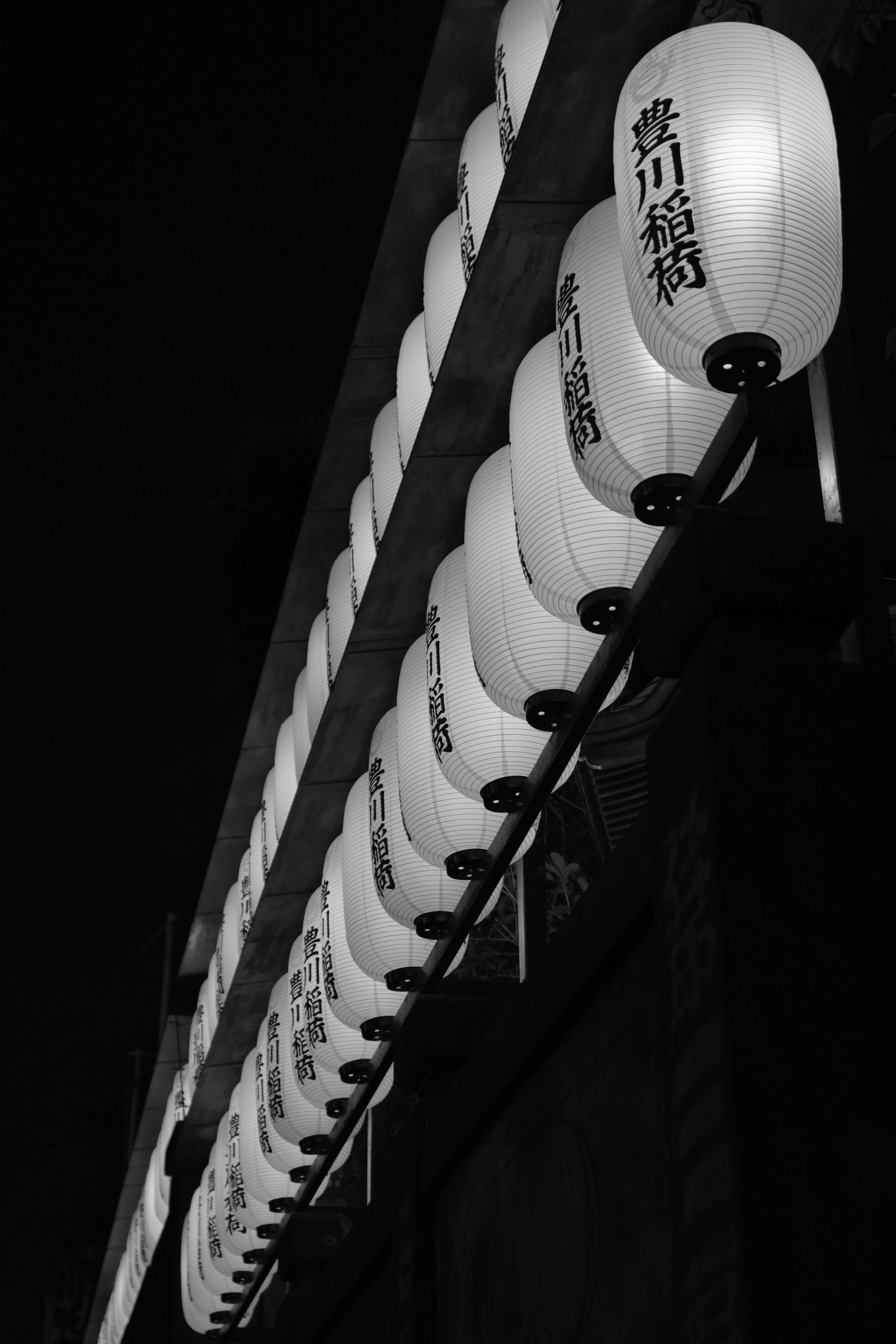 赤い提灯の列と提灯に描かれた文字のある夜の参道